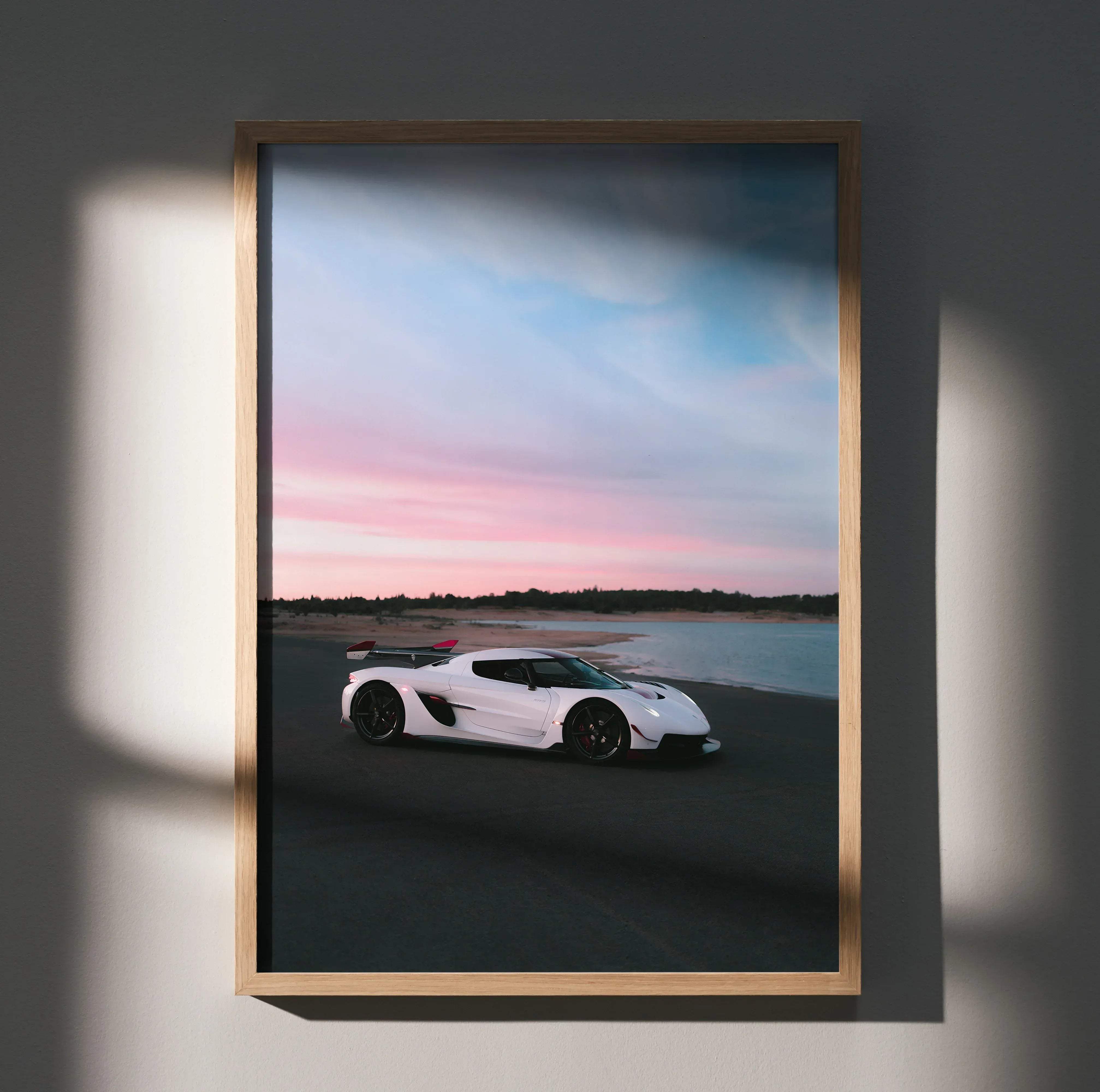 A framed high resolution koenigsegg jesko car poster of a white hypercar parked on a beach at sunset