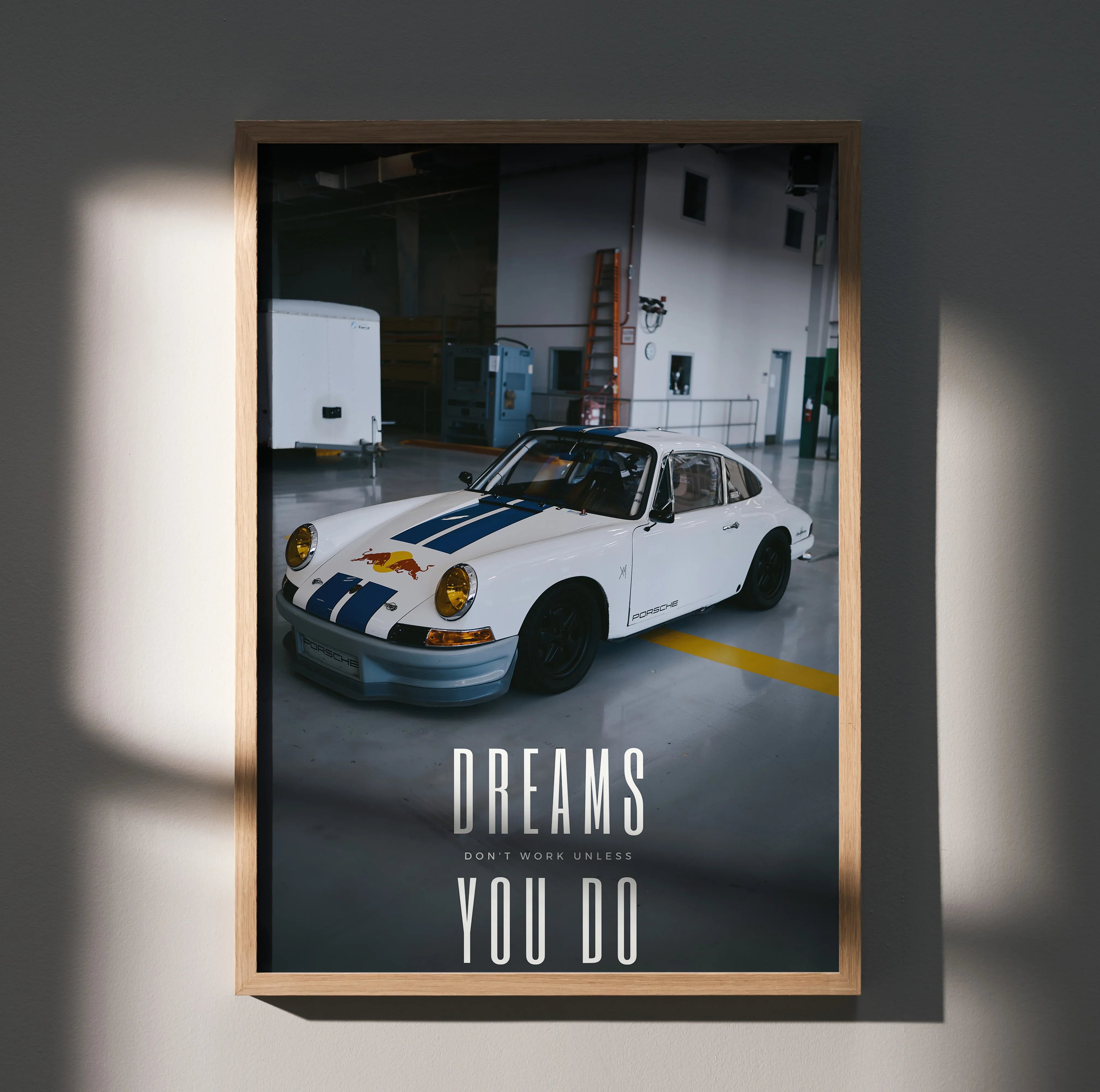 Motivational poster wall art featuring a classic white Porsche 911 with blue racing stripes in a garage setting.