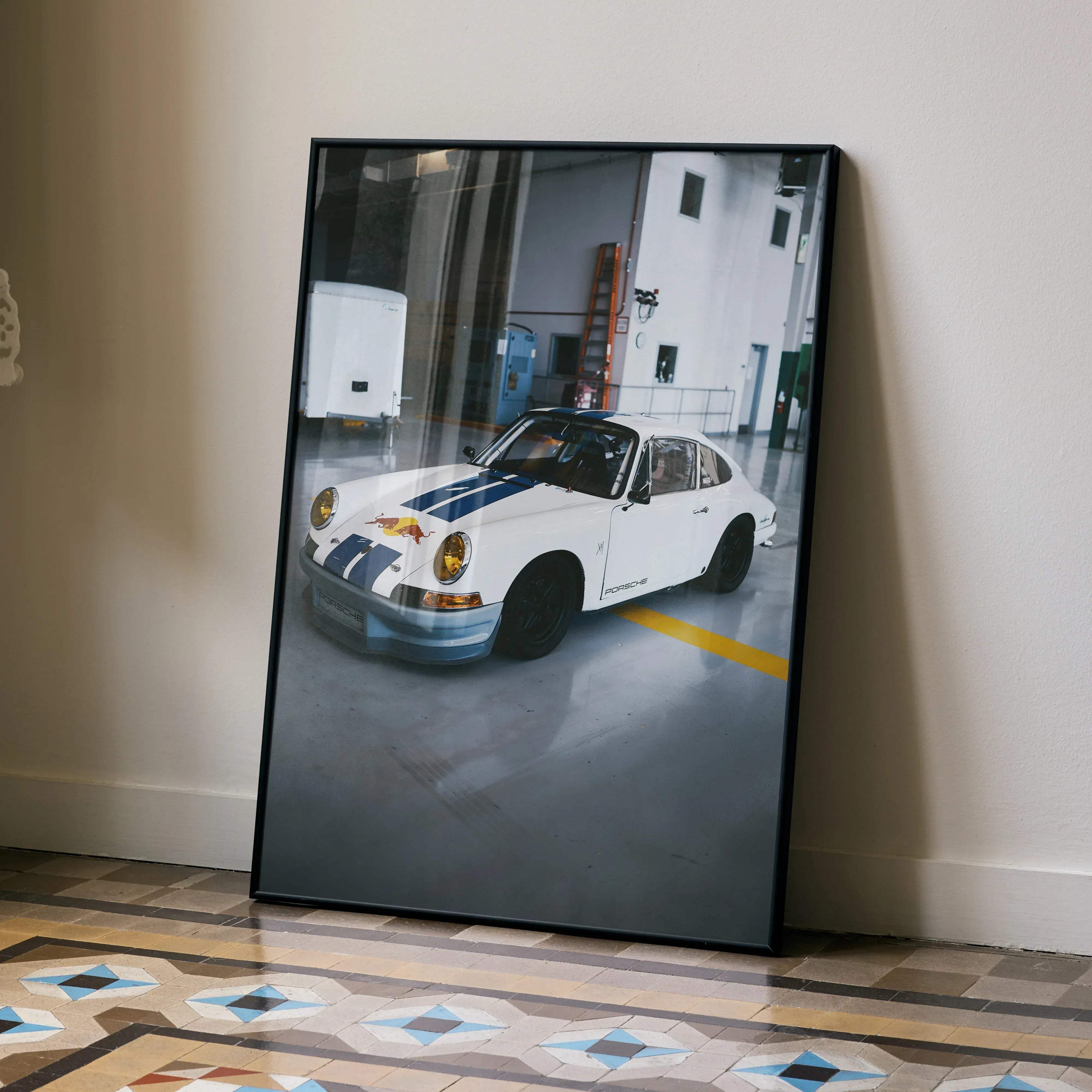 Black-framed photograph of white Porsche 911 with blue racing stripes and red Bull logo in high resolution poster