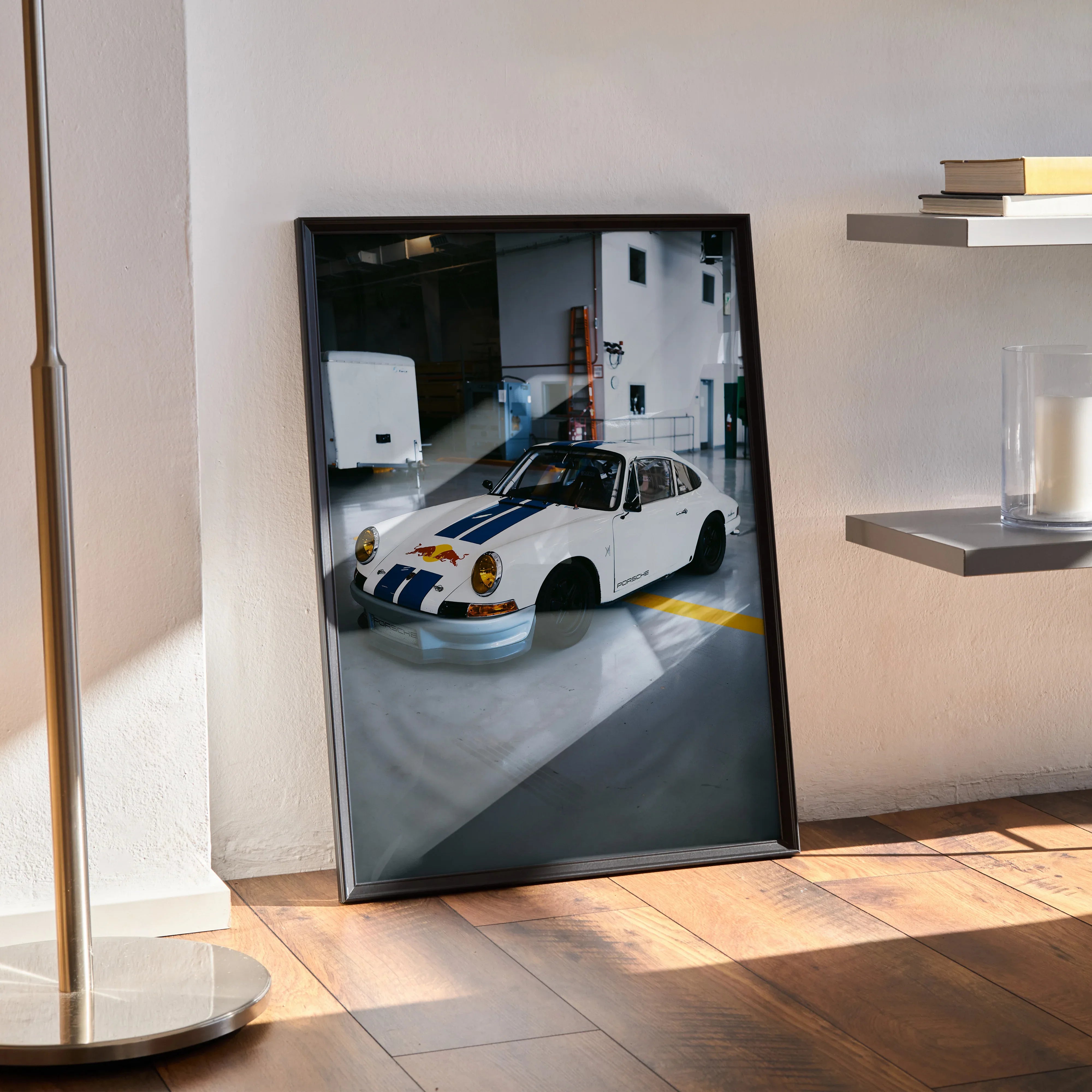 Porsche 911 classic white car poster with blue and yellow stripes framed wall art leaning against wall.