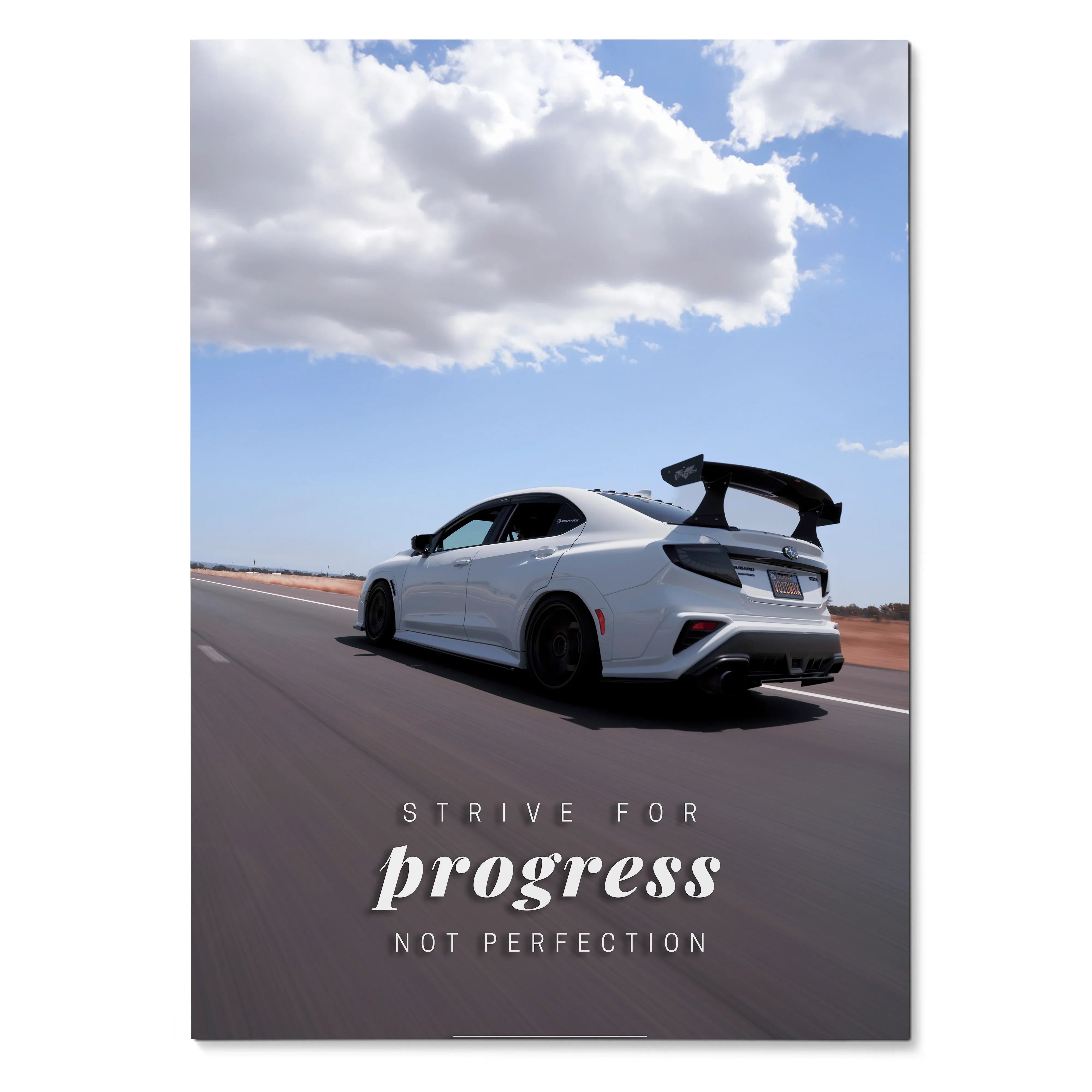 Poster wall art featuring a white Subaru WRX STI on a road with the text "Strive for progress not perfection" under a cloudy .