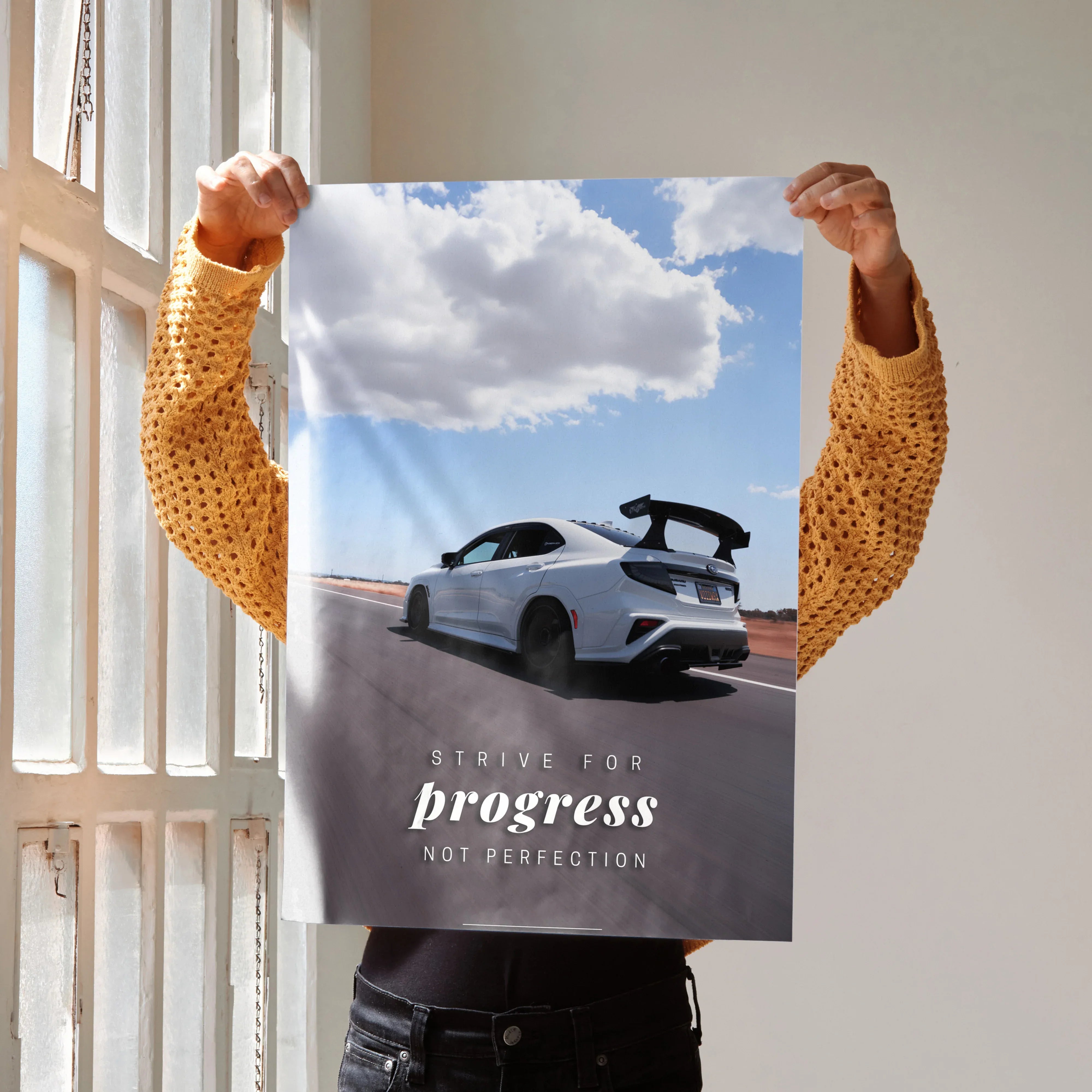 Motivational poster wall art featuring a white Subaru WRX STI on an open road under a cloudy sky with inspiring text.