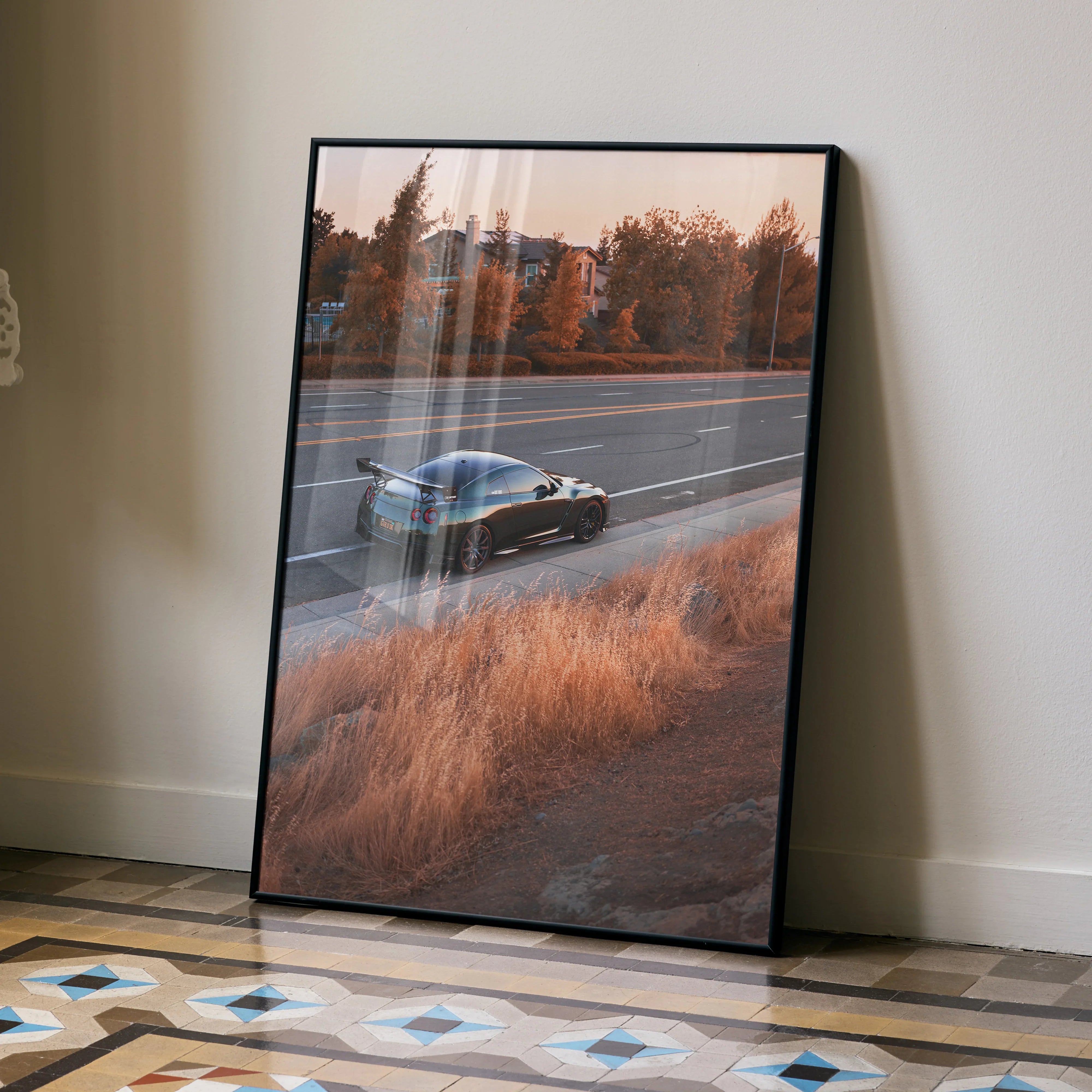 Nissan GTR R35 poster featuring sleek black car on highway at sunset, modern wall art in frame.