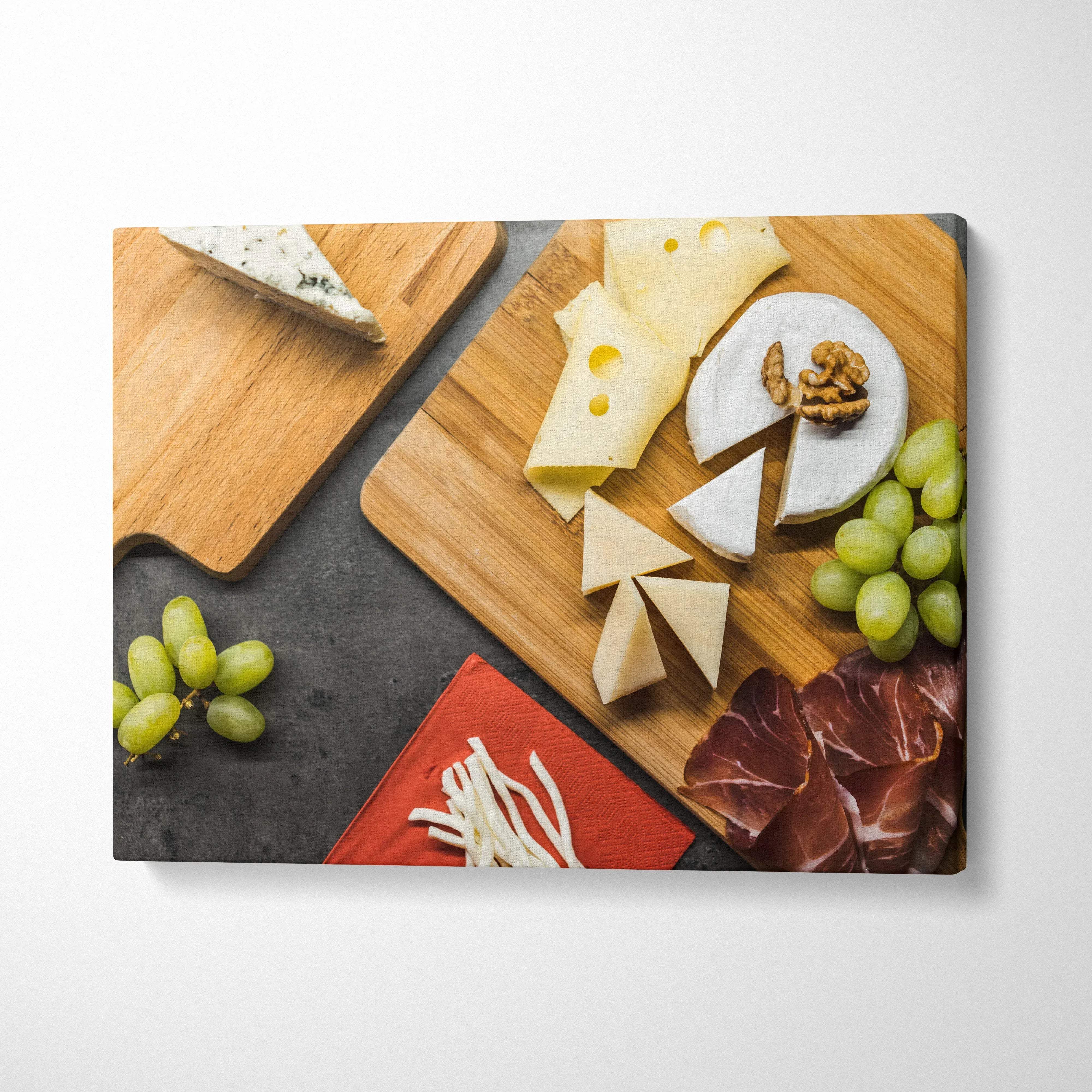 Canvas wall art featuring cheese assortments, grapes, walnuts, and cured meat on wooden boards.