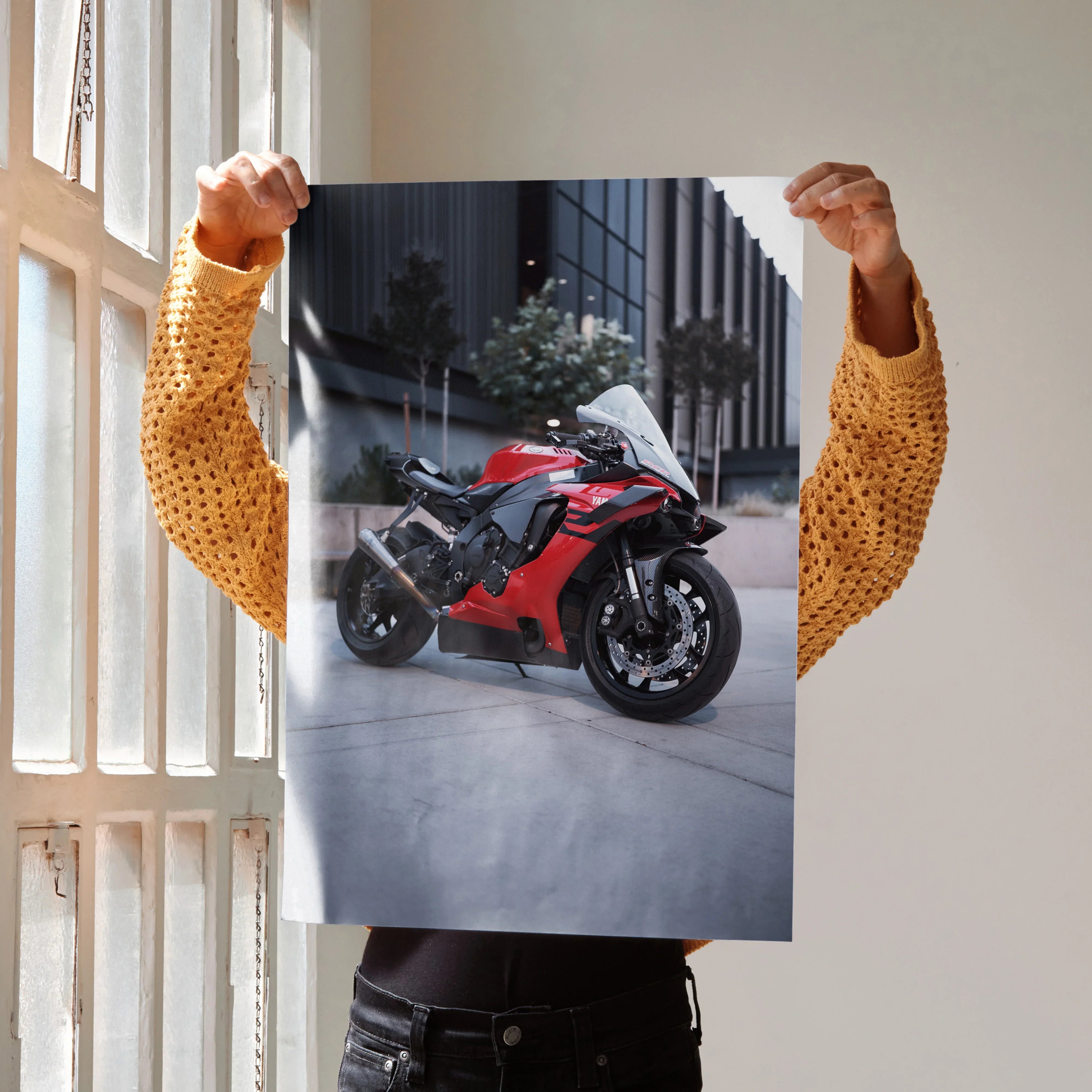 Yamaha R1 red motorcycle poster held indoors by person in mustard sweater, wall art design.