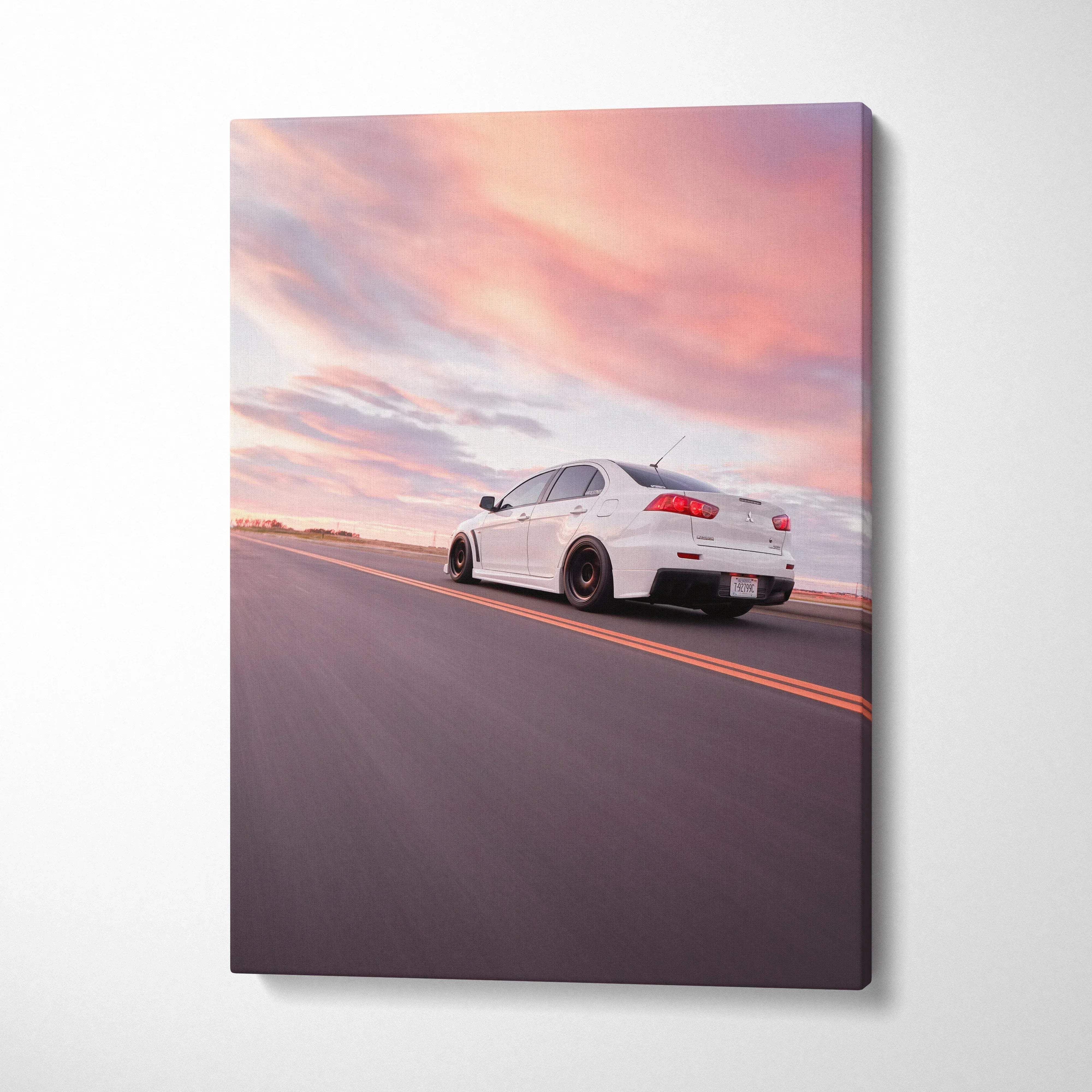 Vertical canvas wall art of a white Mitsubishi Evo 10 driving on an open road at sunset with pink and purple sky.