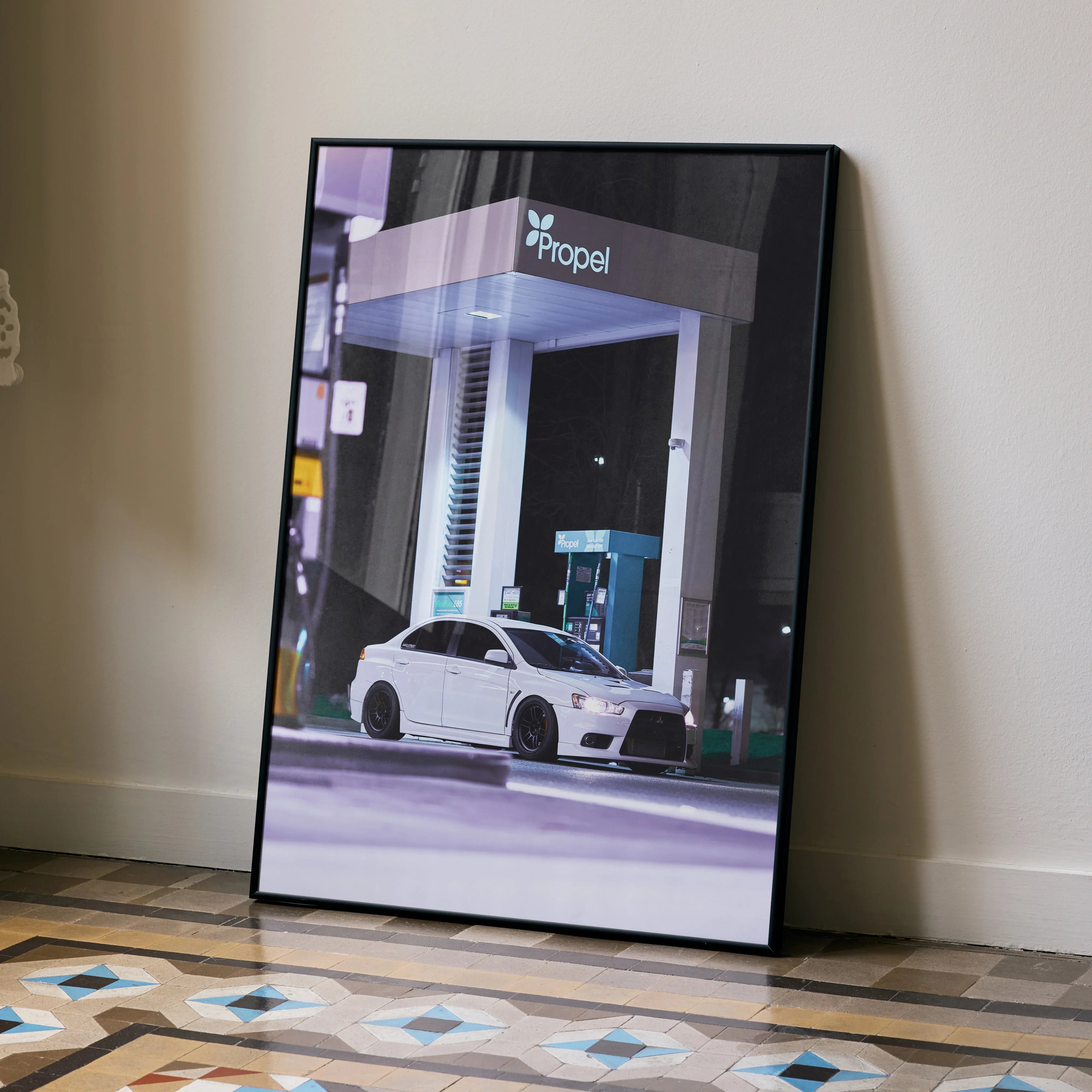 Mitsubishi Evo 10 poster with sleek white car at gas station, modern wall art on floor.
