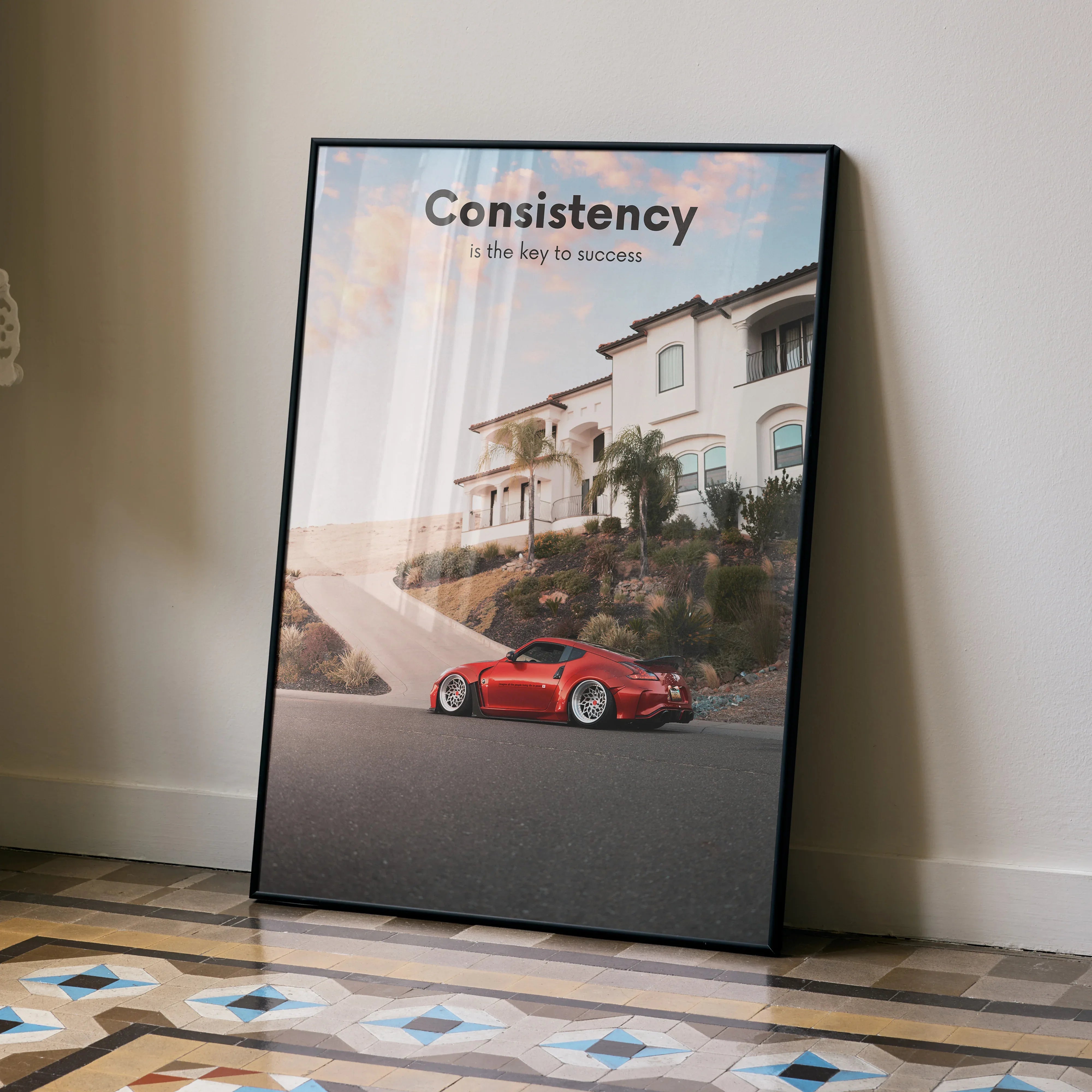 Motivational poster wall art featuring red Nissan 370z parked in front of luxury home with text "Consistency the key to.