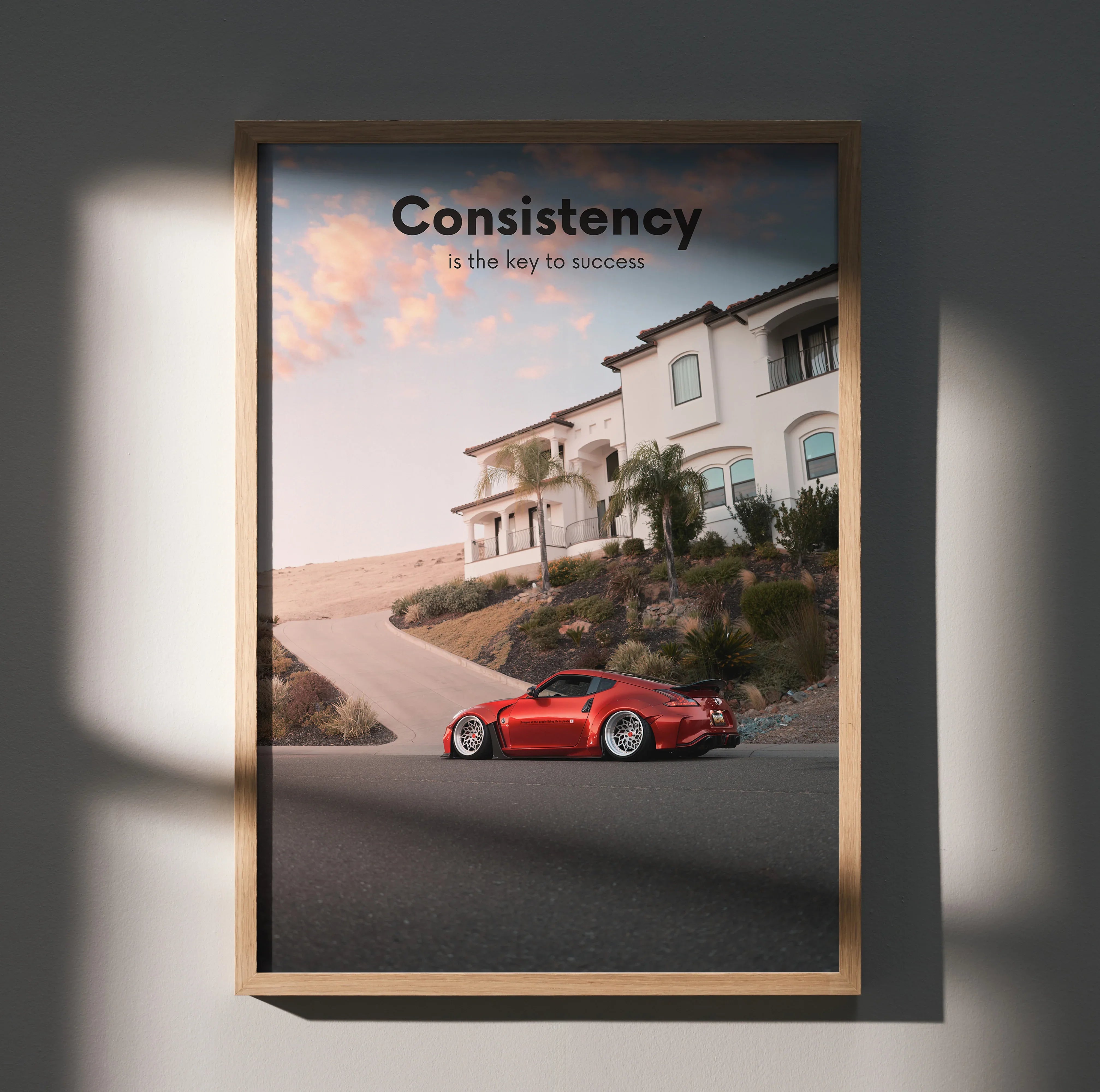 Motivational poster wall art featuring a red Nissan 370z on a residential street with inspiring text "Consistency is the key .