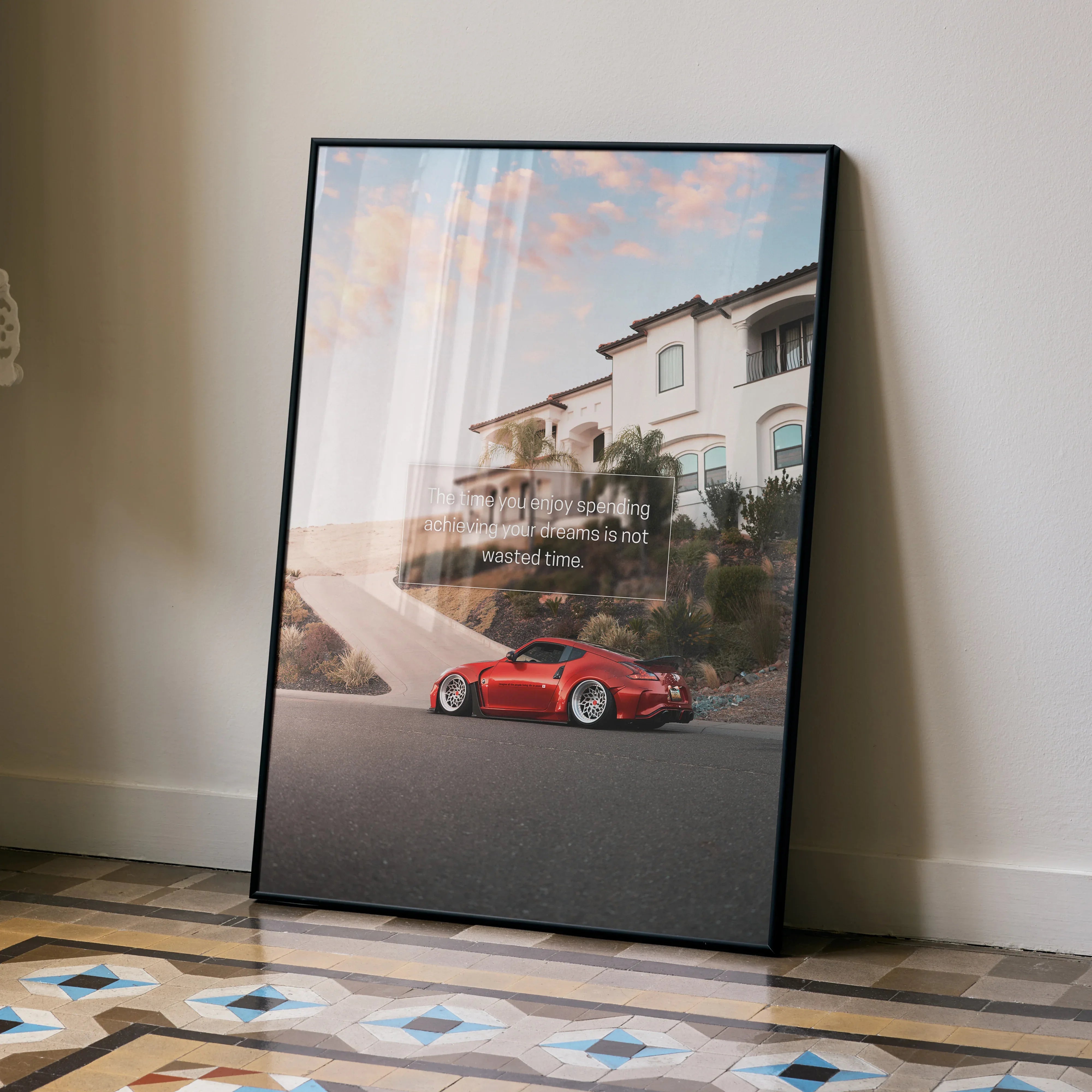 Motivational poster wall art featuring red Nissan 370z parked by luxury house at sunset.