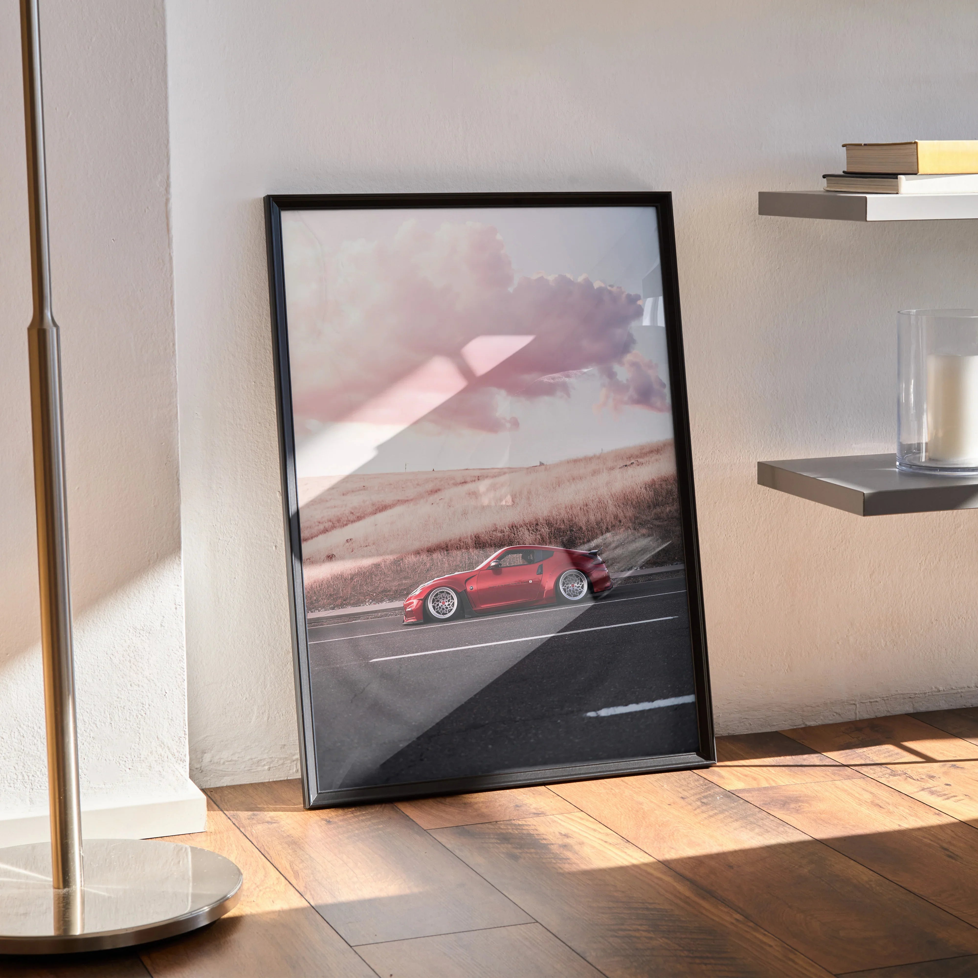 Nissan 370z poster with sunset backdrop in black frame leaning on wooden floor wall art.