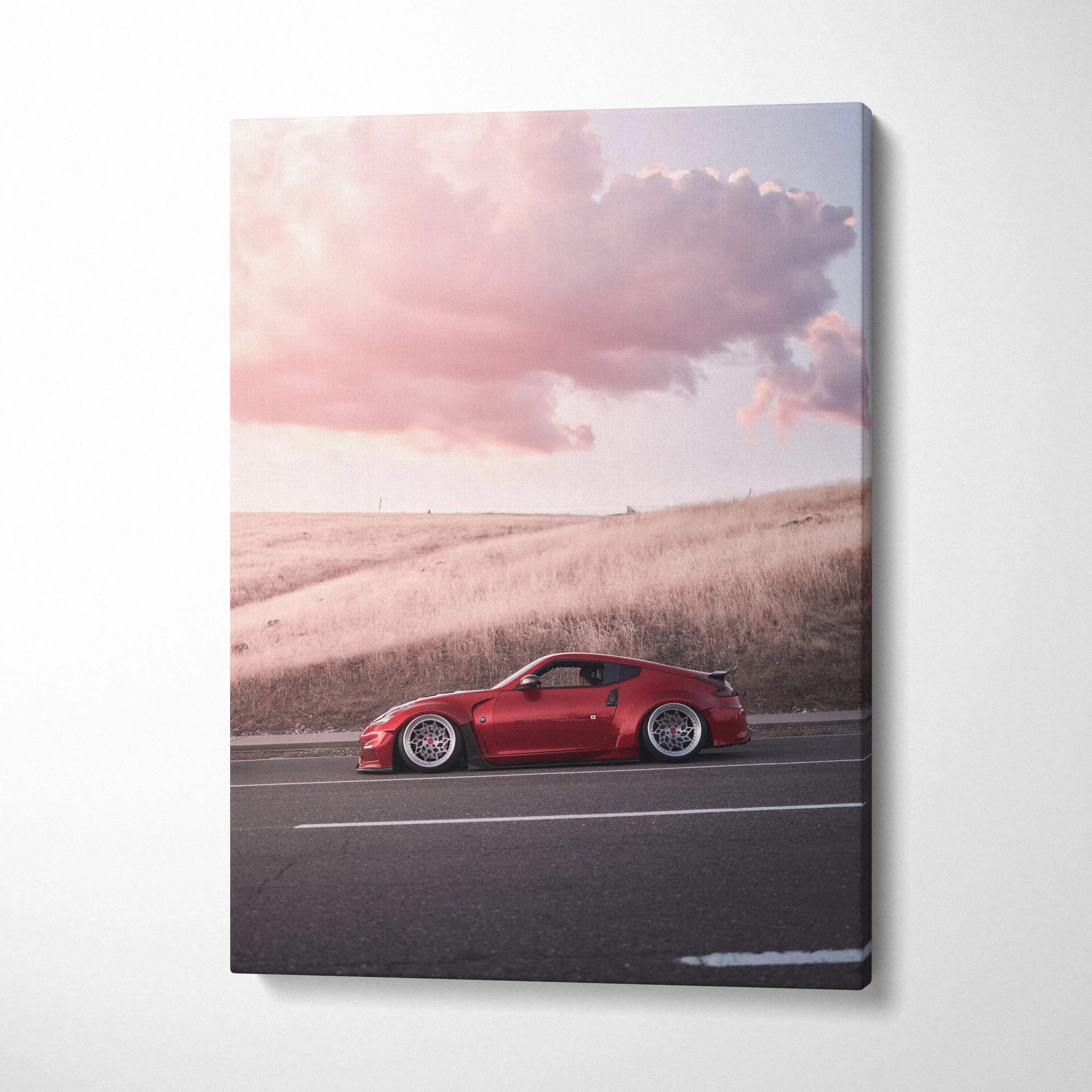 Red Nissan 370z driving on road at sunset with pink clouds canvas wall art.