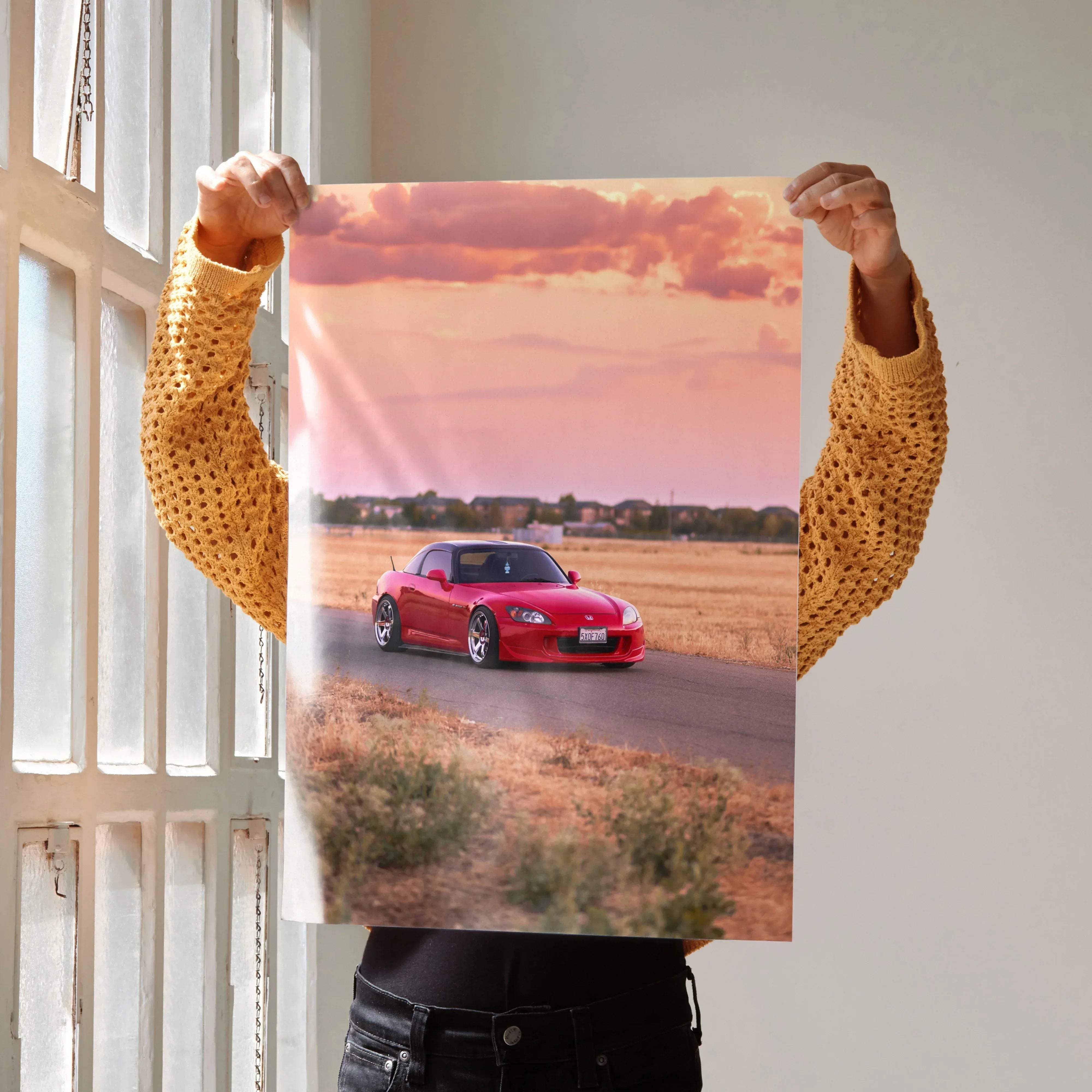 A vibrant red Honda S2000 sports car in motion on a sunlit road under a pink and orange sky poster