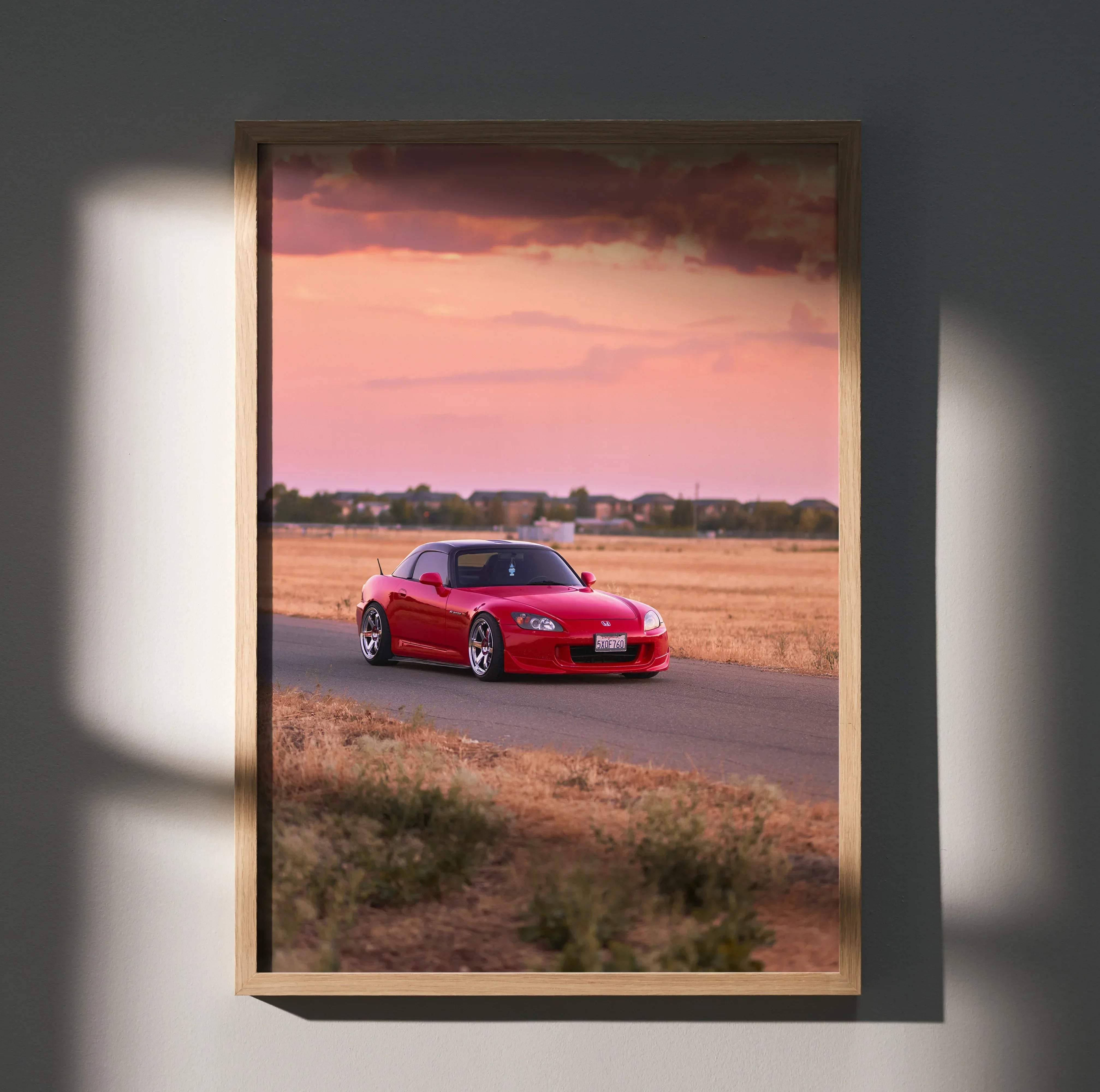 Framed photograph poster of red honda s2000 sports car against pink and orange sunset sky for wall decor