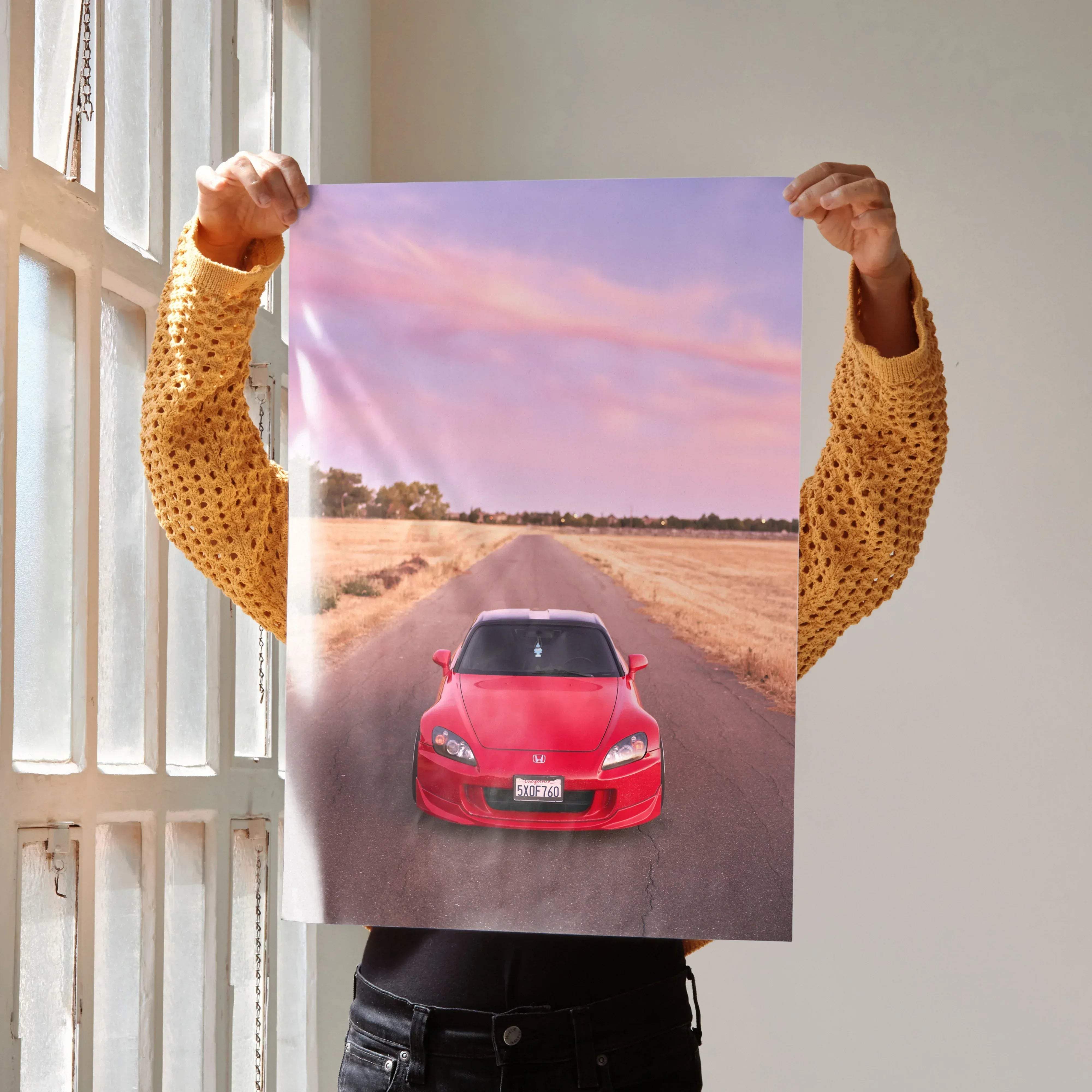 A vibrant red Honda S2000 sports car poster with glossy finish displayed against a soft pink purple twilight sky