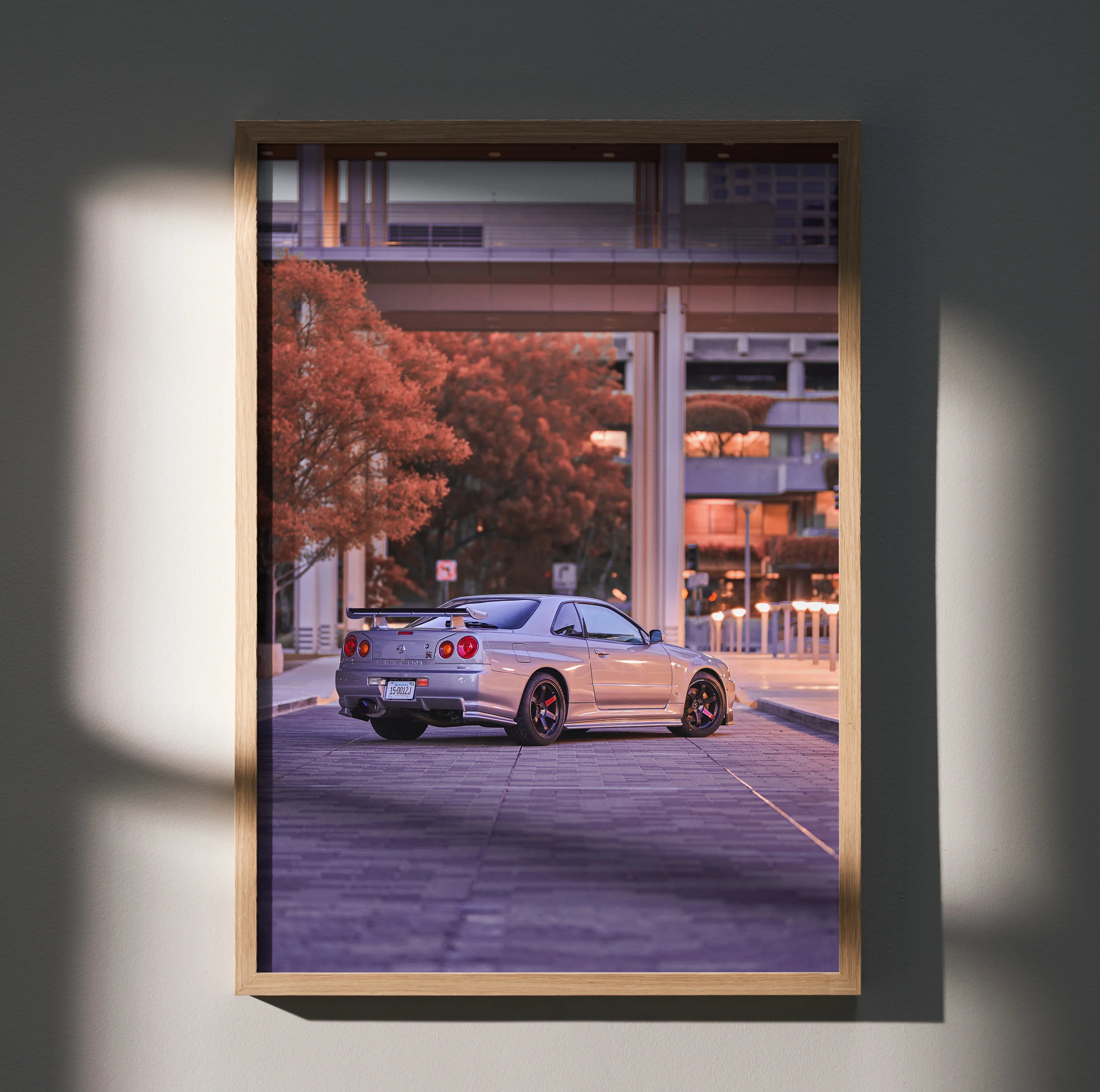 Nissan R34 GTR Skyline poster wall art featuring a silver car in an urban setting with autumn trees.
