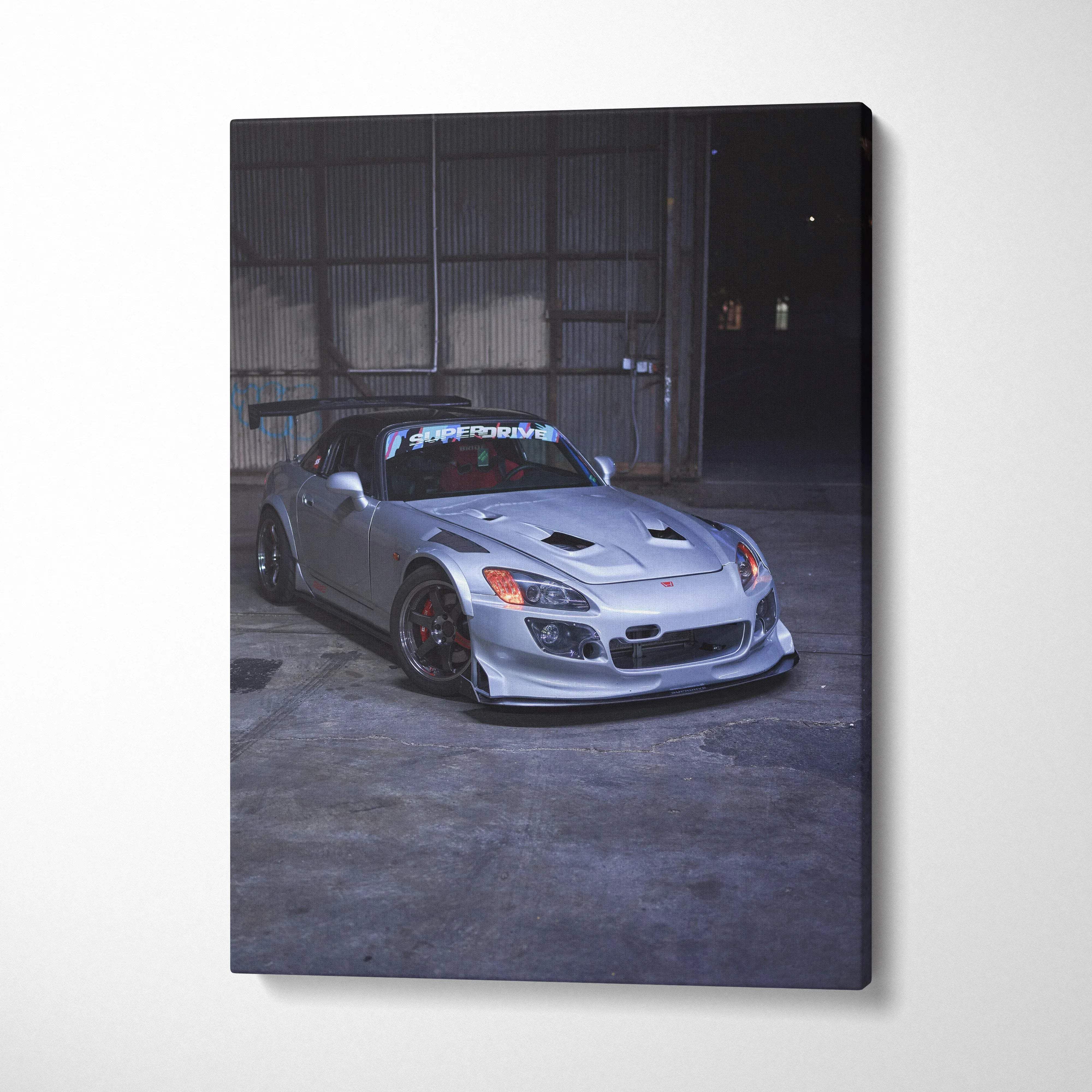 Canvas wall art featuring a silver honda s2000 sports car with black roof and red brake calipers in a garage setting