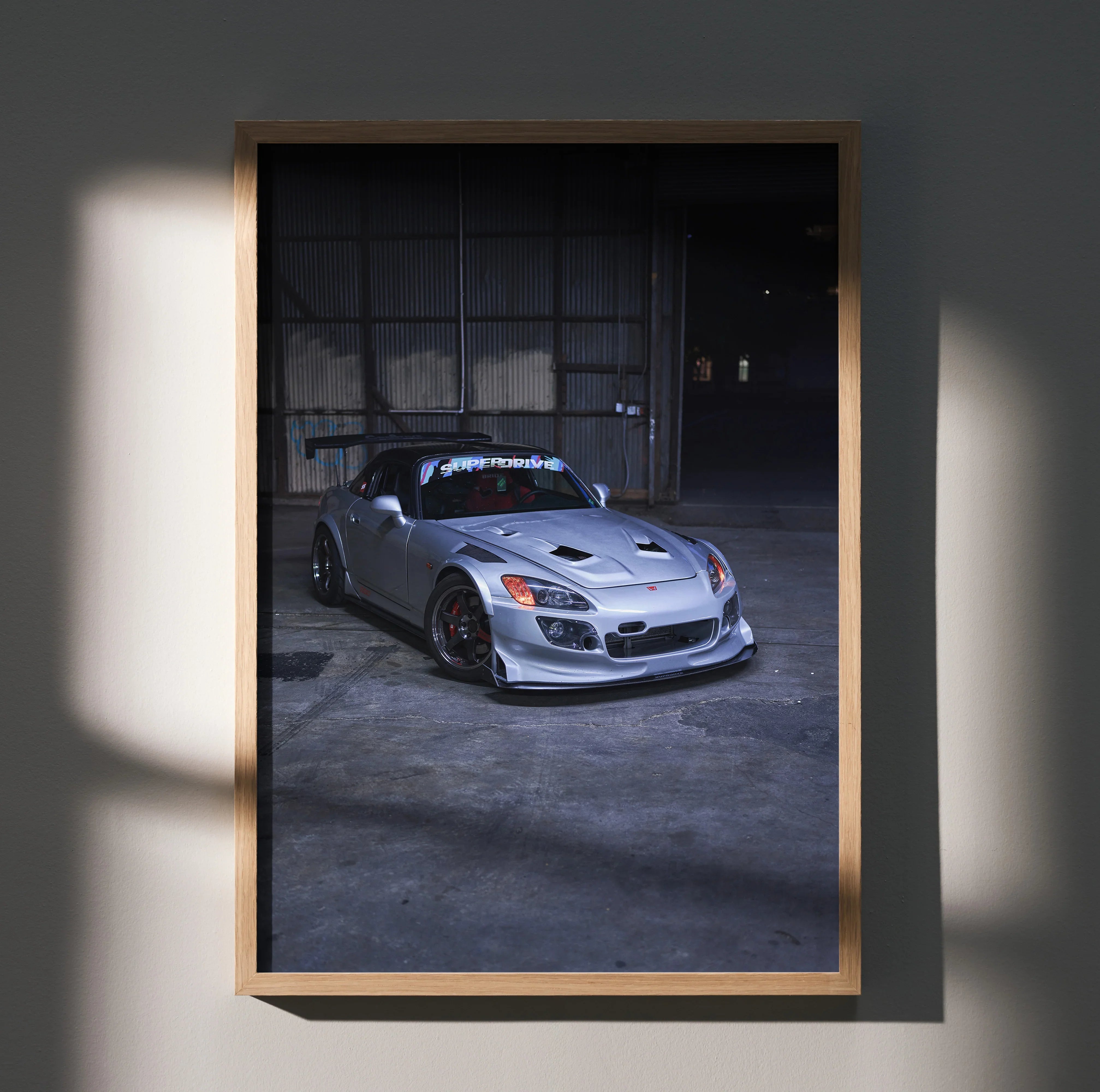 Honda S2000 sports car poster wall art with dark moody garage background in wooden frame.