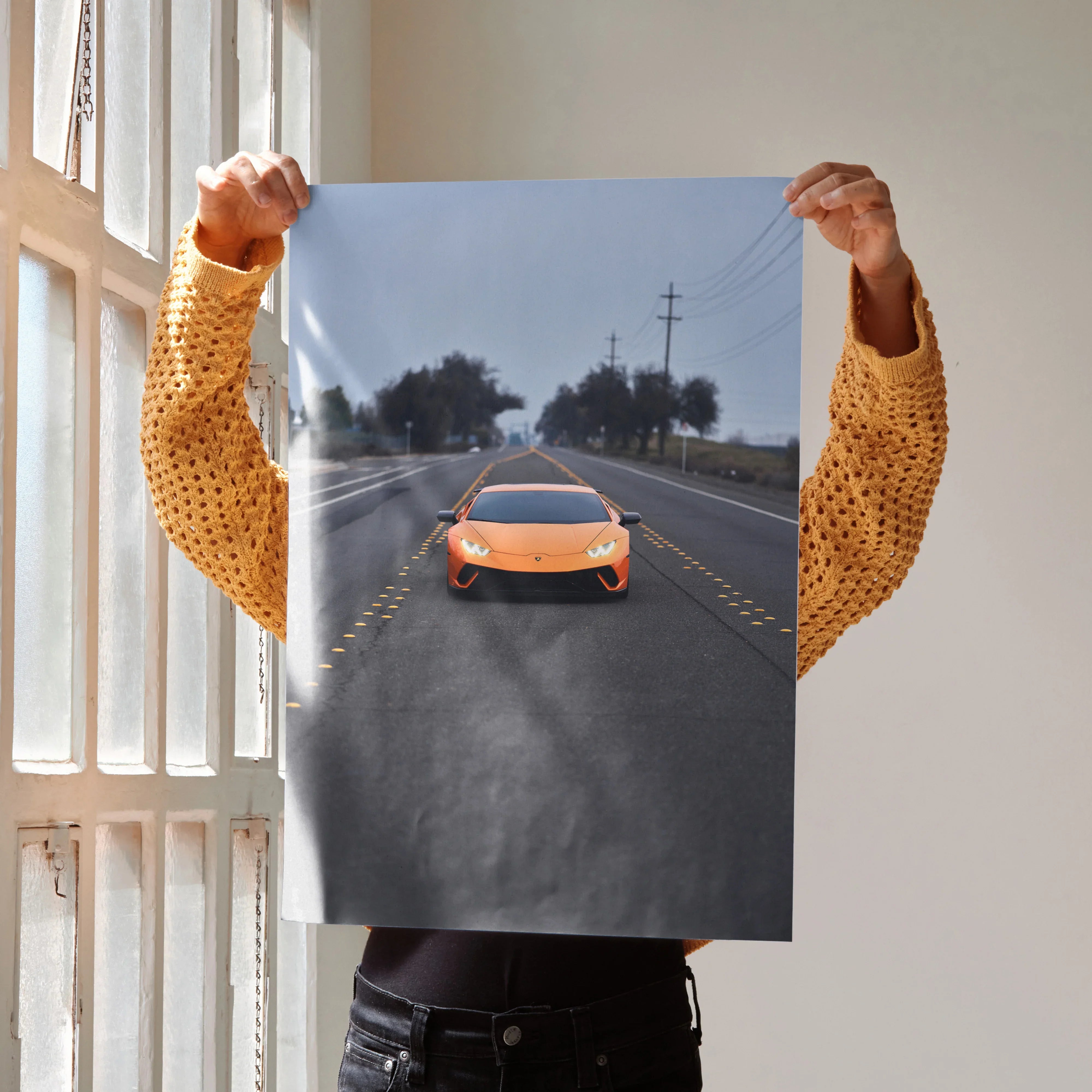 Lamborghini Huracan poster as wall art with orange sports car on open highway under overcast sky.