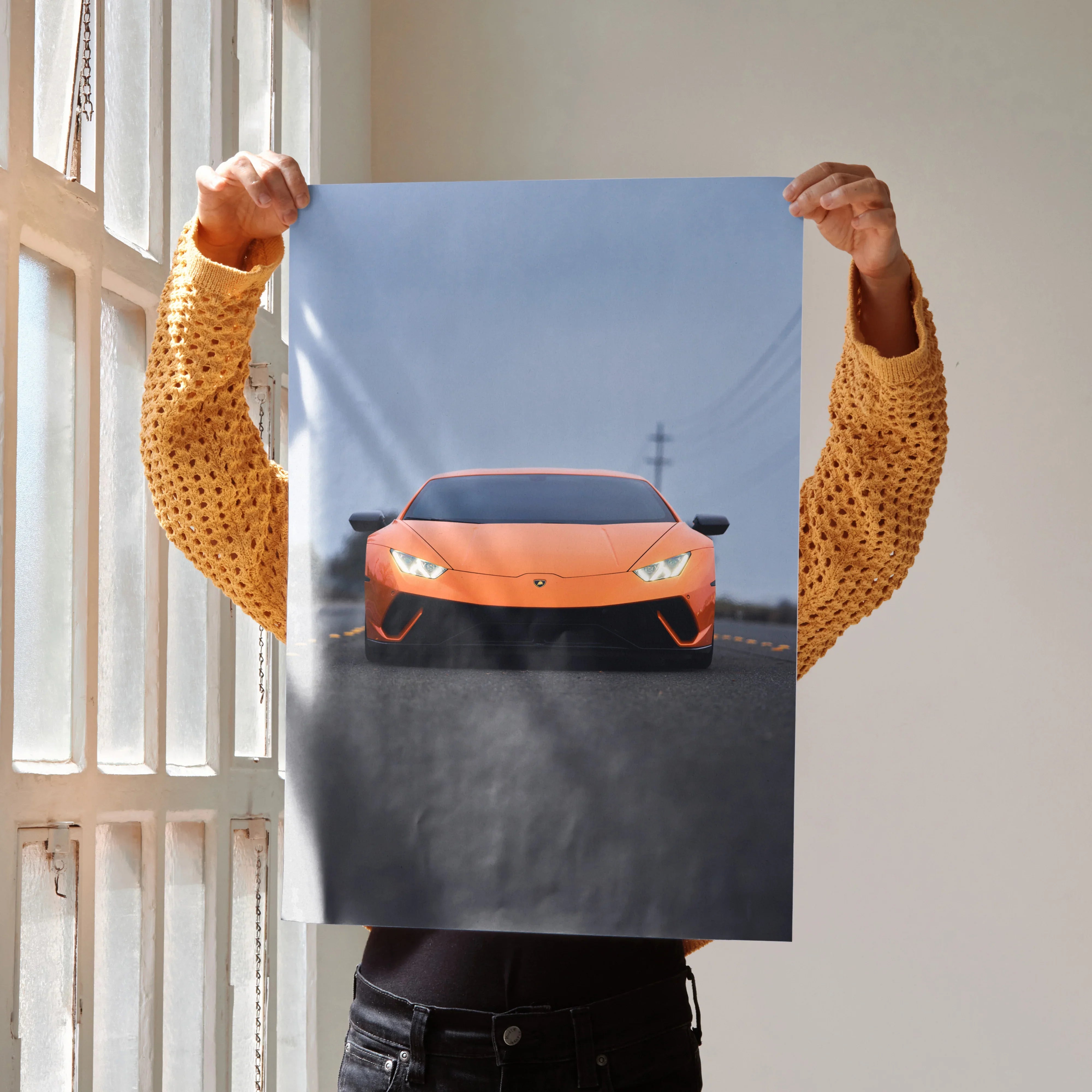 Lamborghini Huracan orange sports car poster held indoors, modern wall art with sleek automotive design.