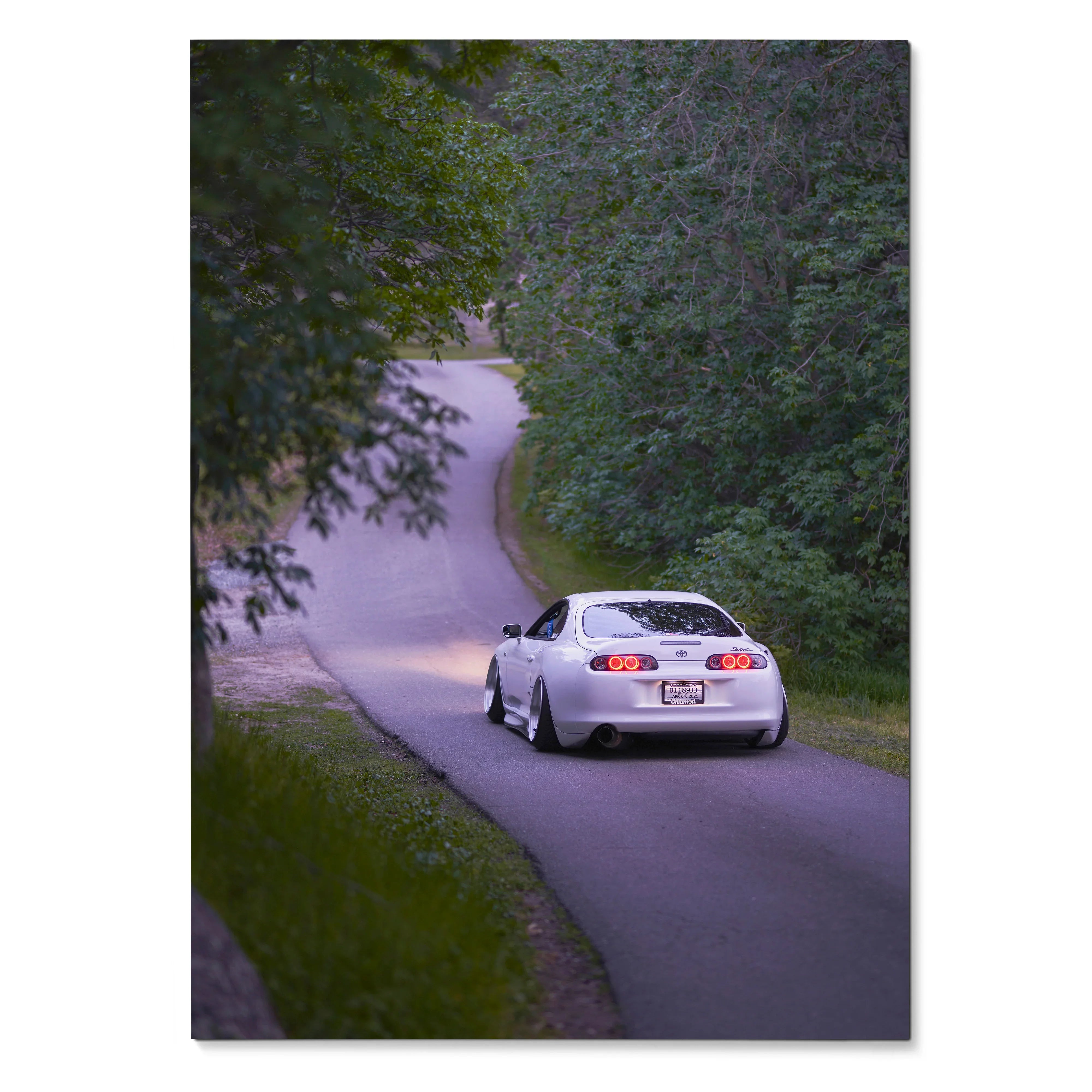 Toyota Supra MK4 driving on a winding road surrounded by green trees poster wall art.