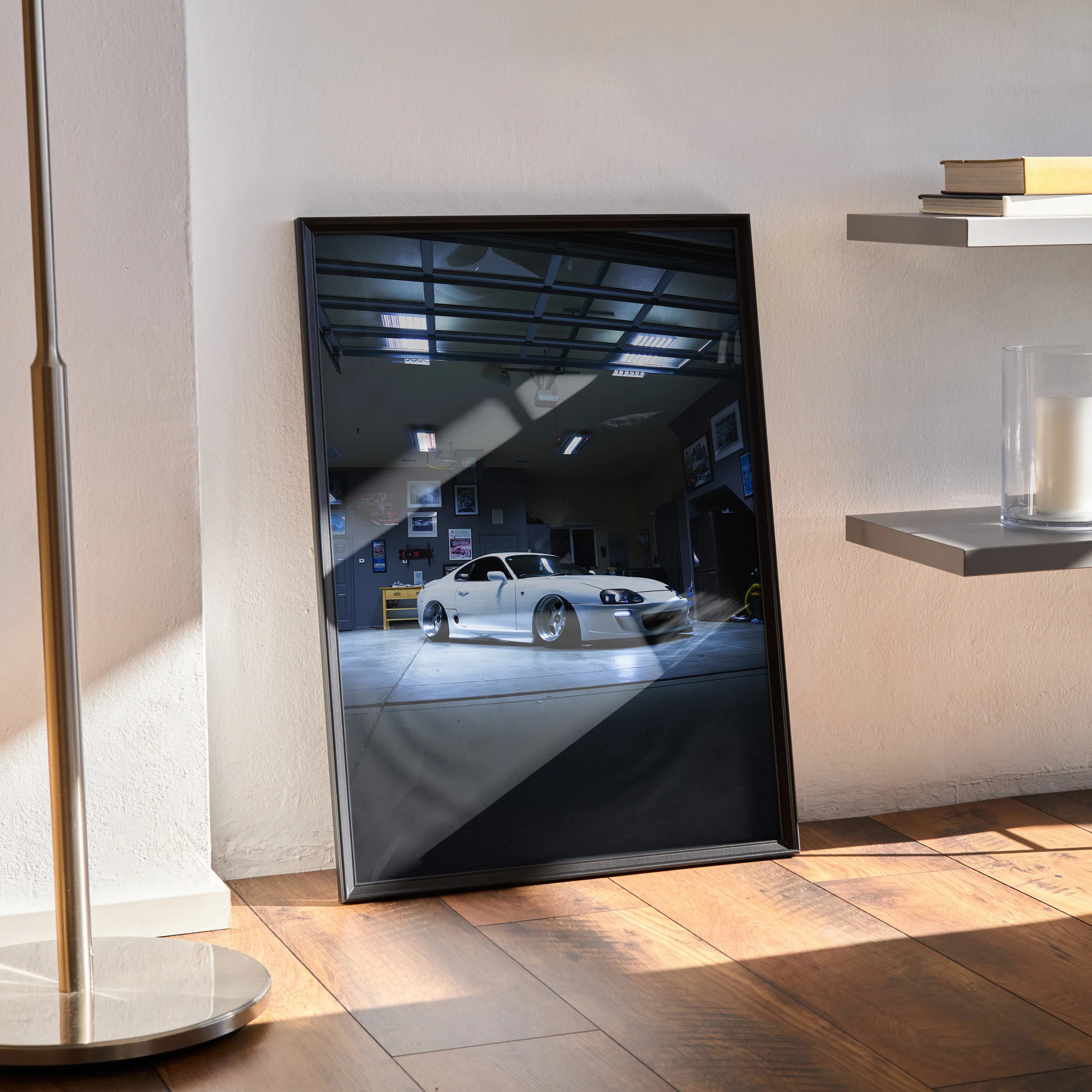 Toyota Supra MK4 poster wall art in black frame leaning against white wall on wooden floor.