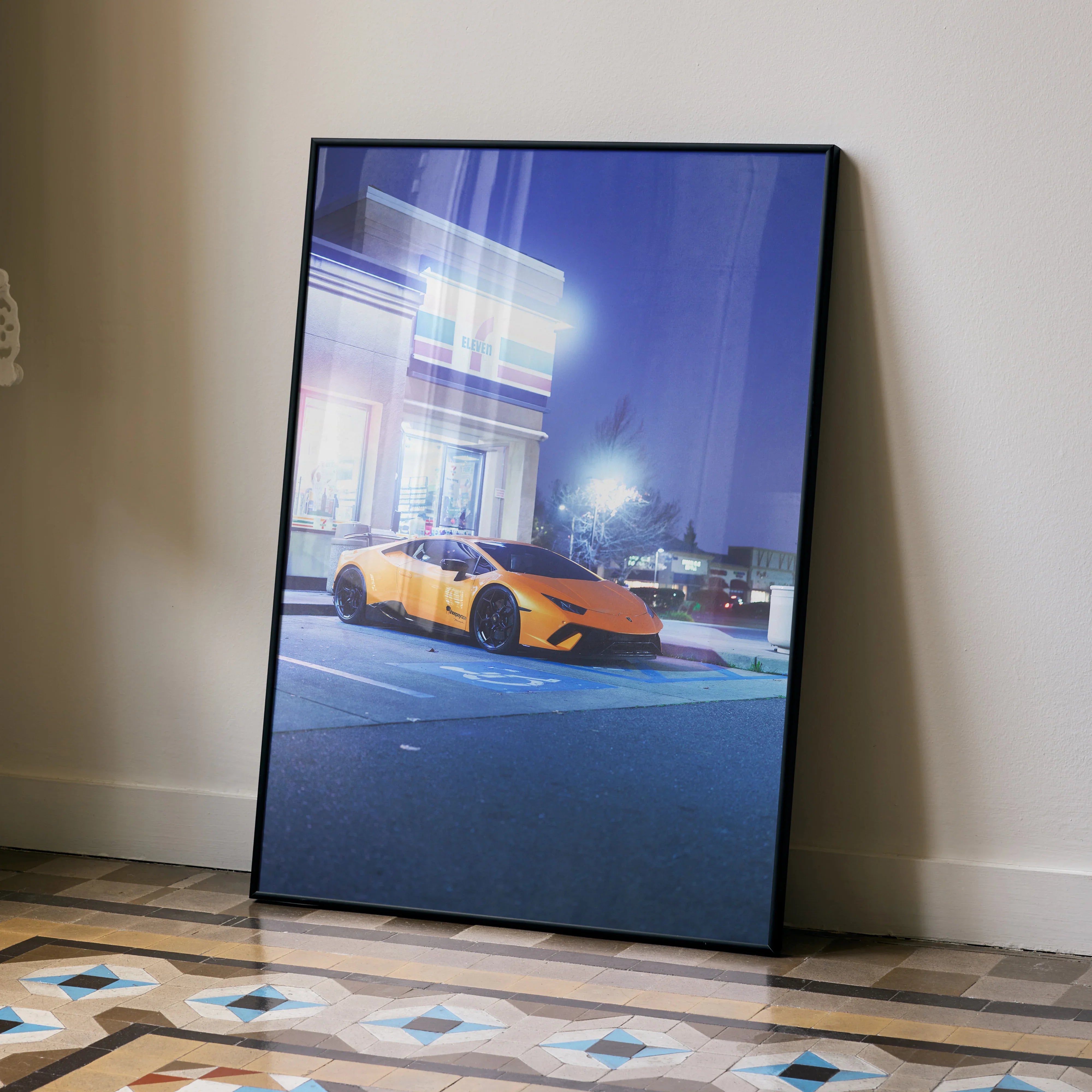 Lamborghini Huracan in vibrant orange parked at night poster wall art with modern building backdrop.