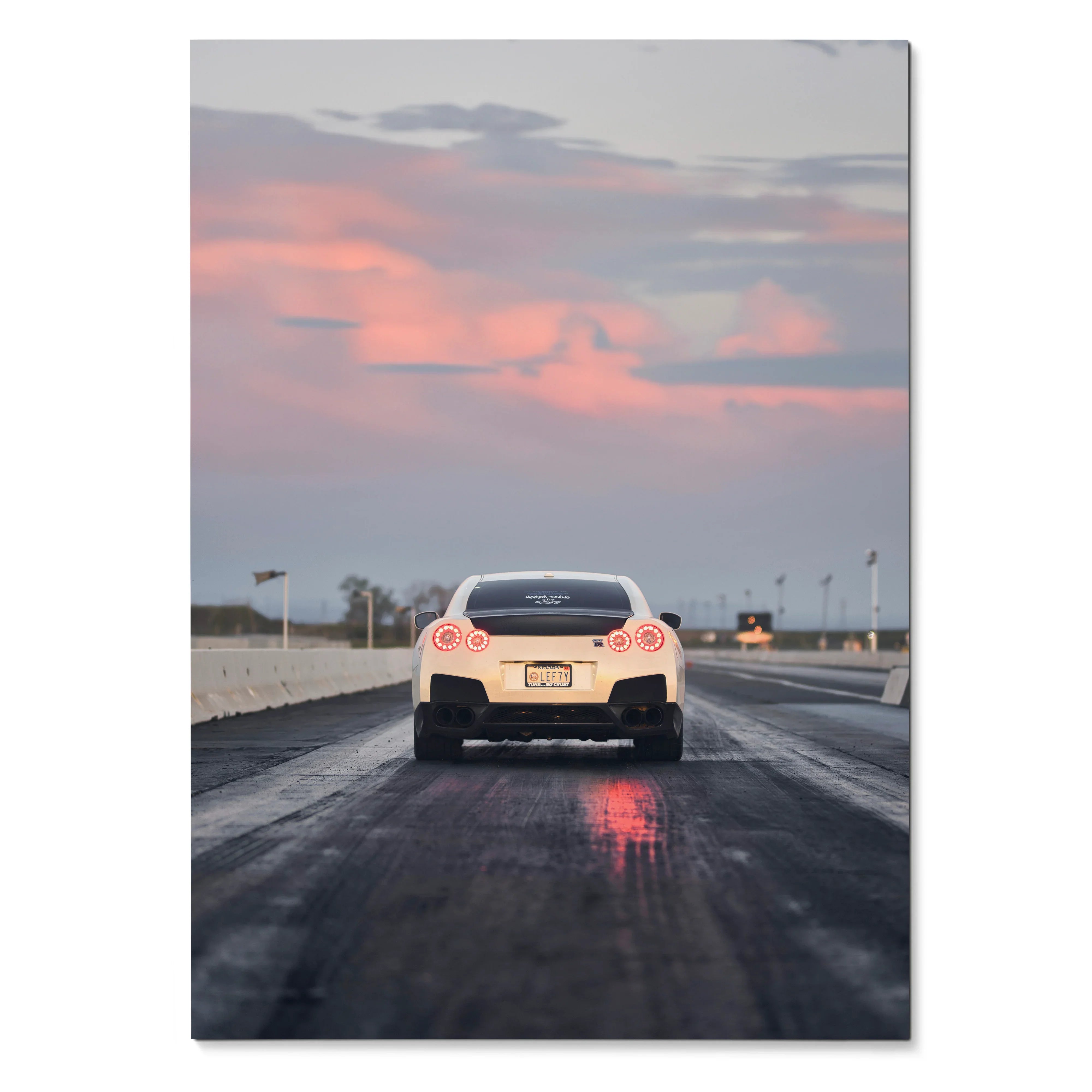 Nissan GTR R35 rear view on wet road at sunset poster wall art with pink sky clouds.