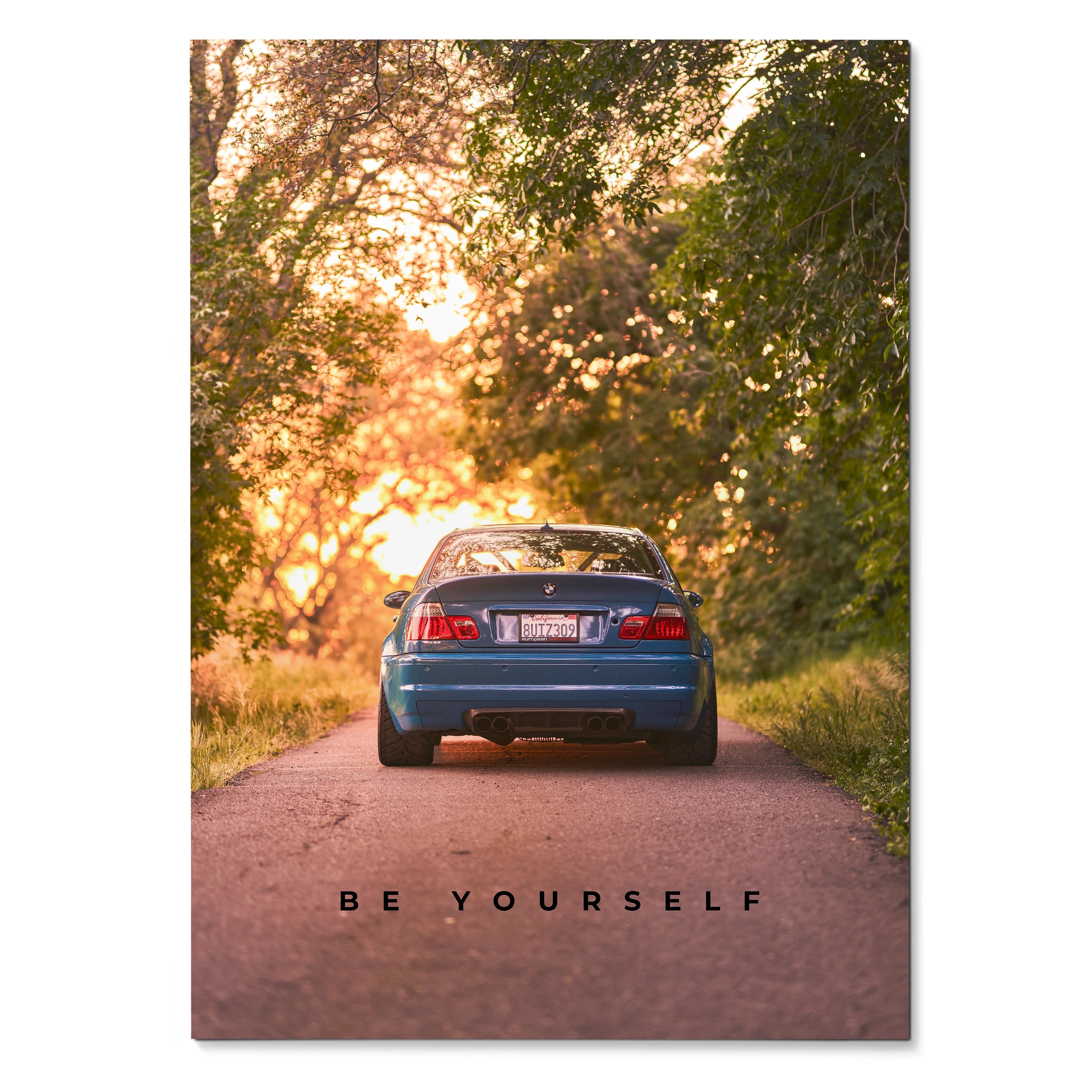 Motivational poster wall art featuring rear view of blue BMW E46 M3 on tree-lined road at sunset with "Be Yourself" text.