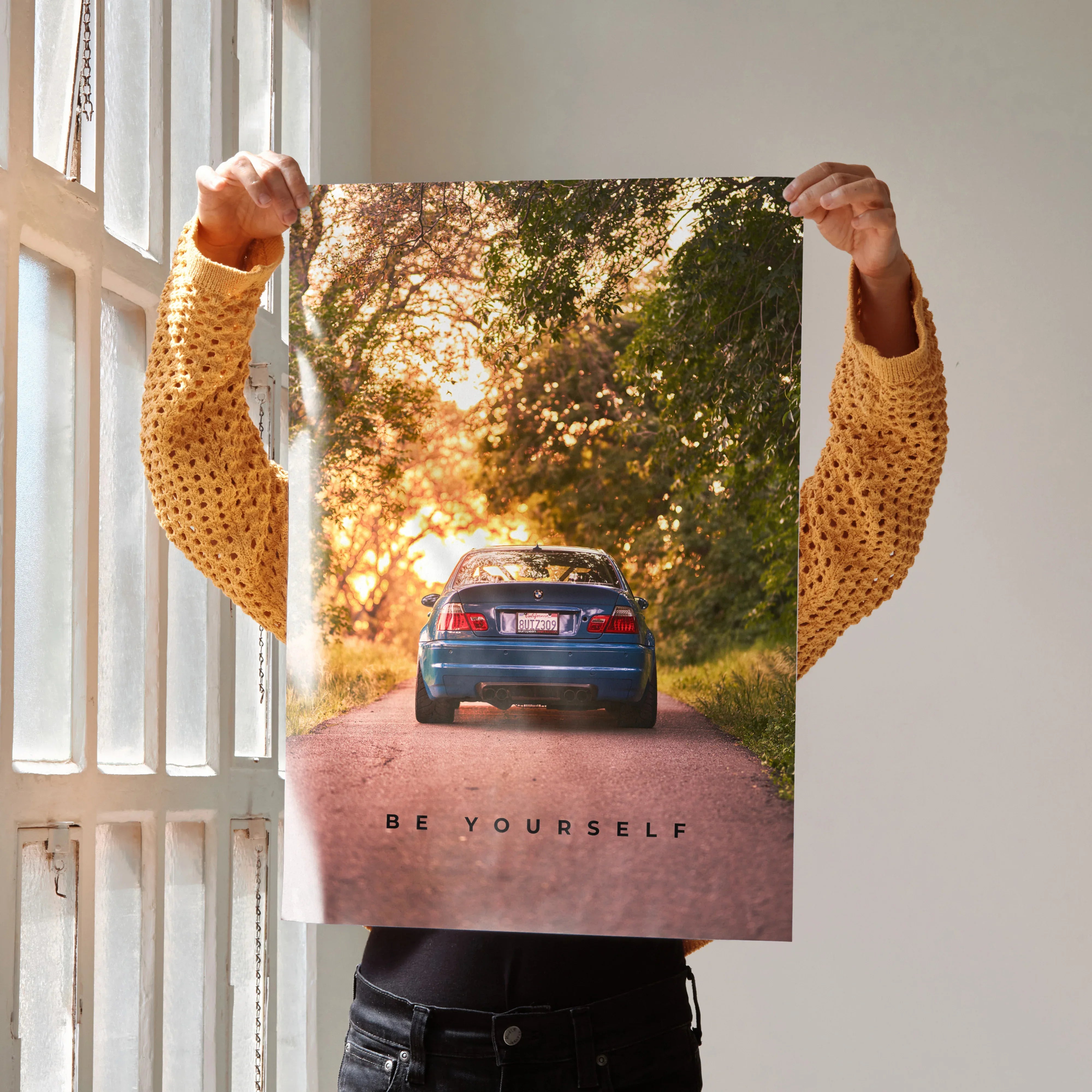 Motivational poster wall art featuring rear view of blue BMW E46 M3 on tree-lined road with inspiring text "Be Yourself".