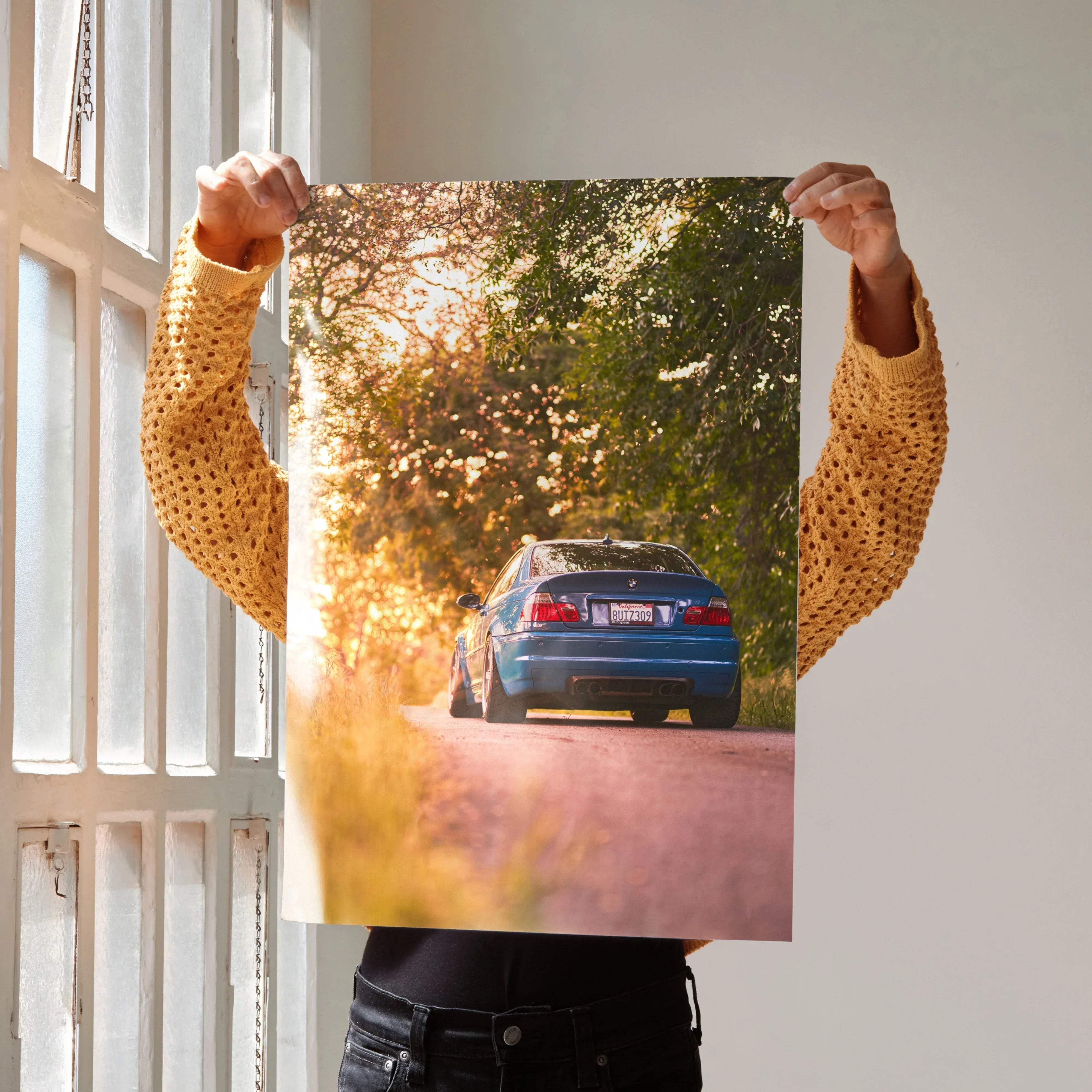 Rear view of a vibrant blue bmw m3 sedan on a sun-dappled dirt road in bmw inspired e46 m3 wall art masterpiece 010