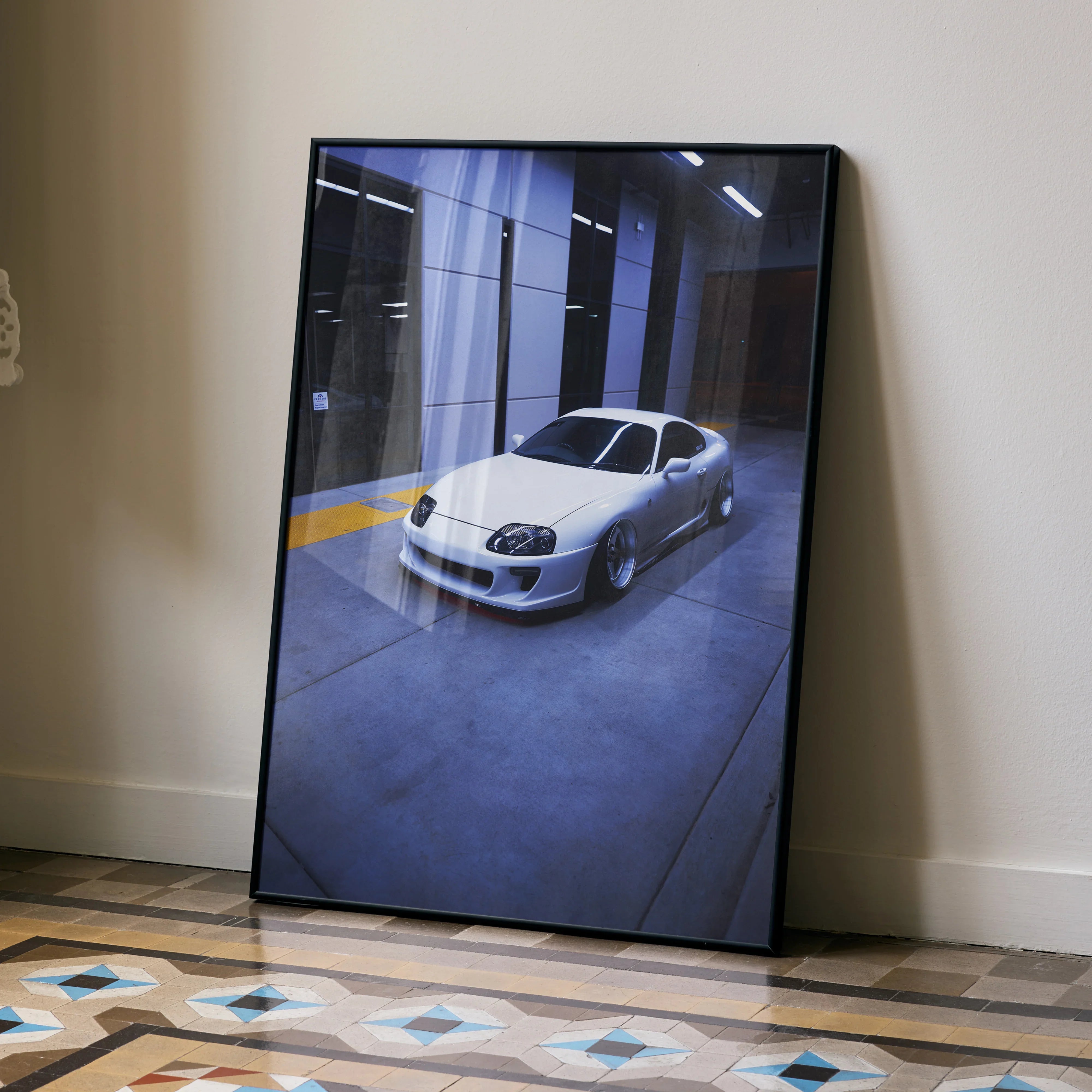 Toyota Supra MK4 in silver parked indoors, high resolution poster wall art leaning on wall.