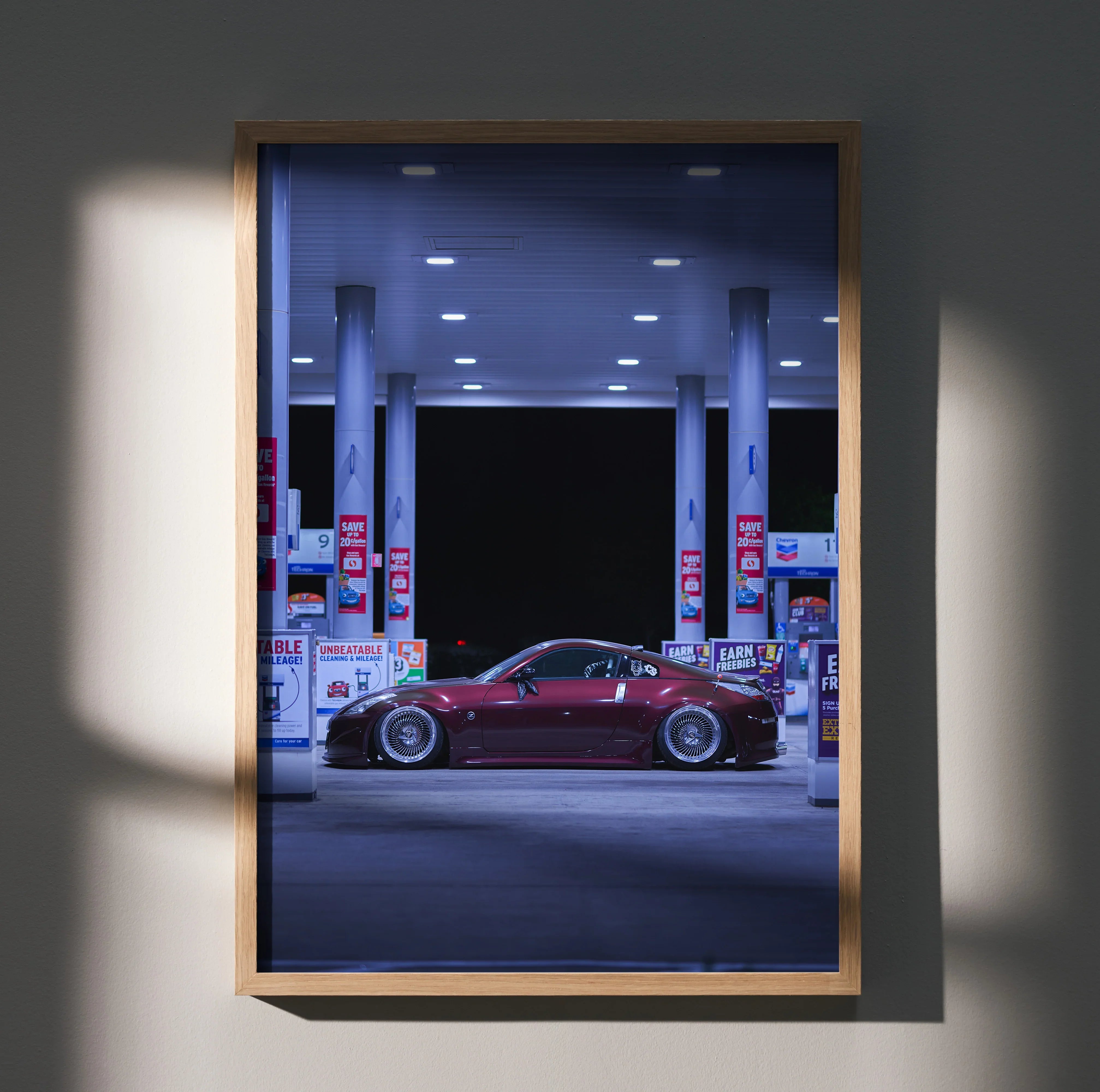 Red Nissan 350Z parked at gas station at night poster wall art in wooden frame.