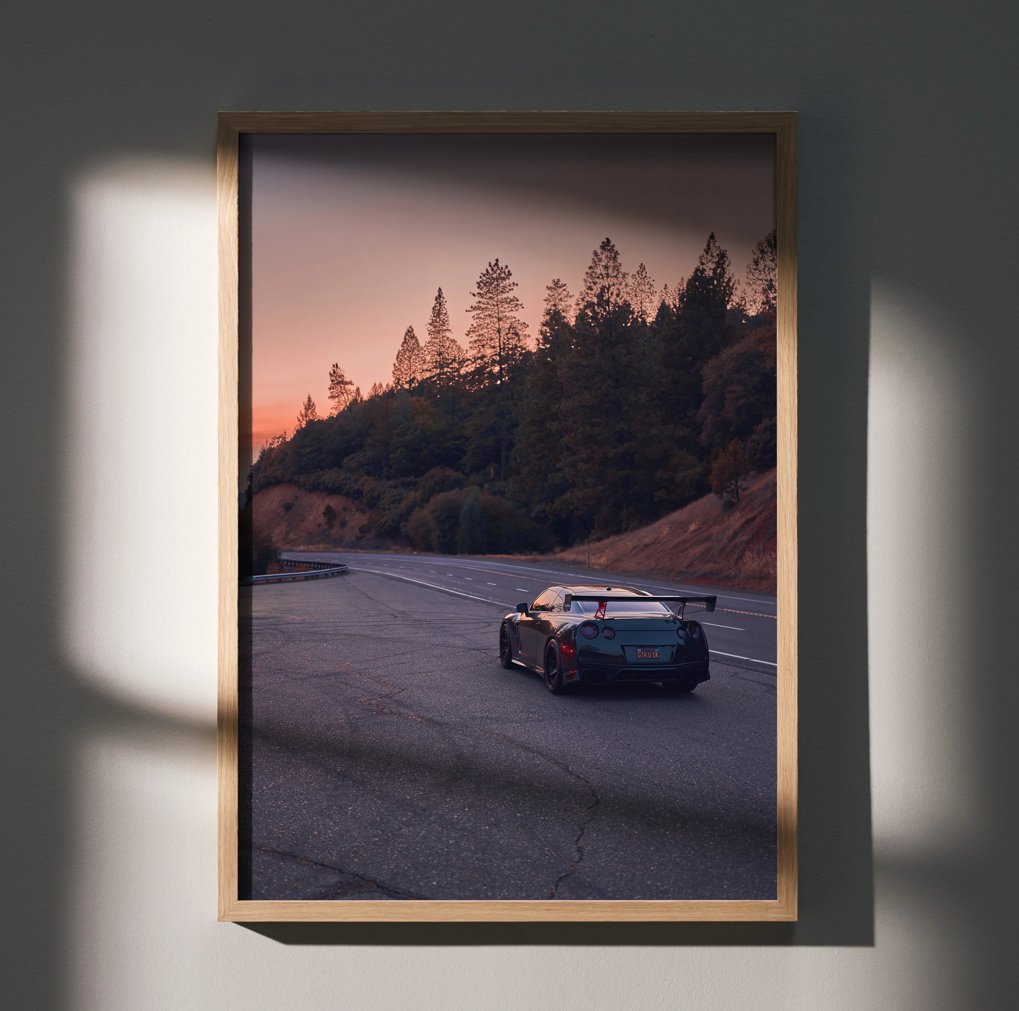 Nissan GTR R35 driving on winding road at sunset poster wall art in wooden frame.