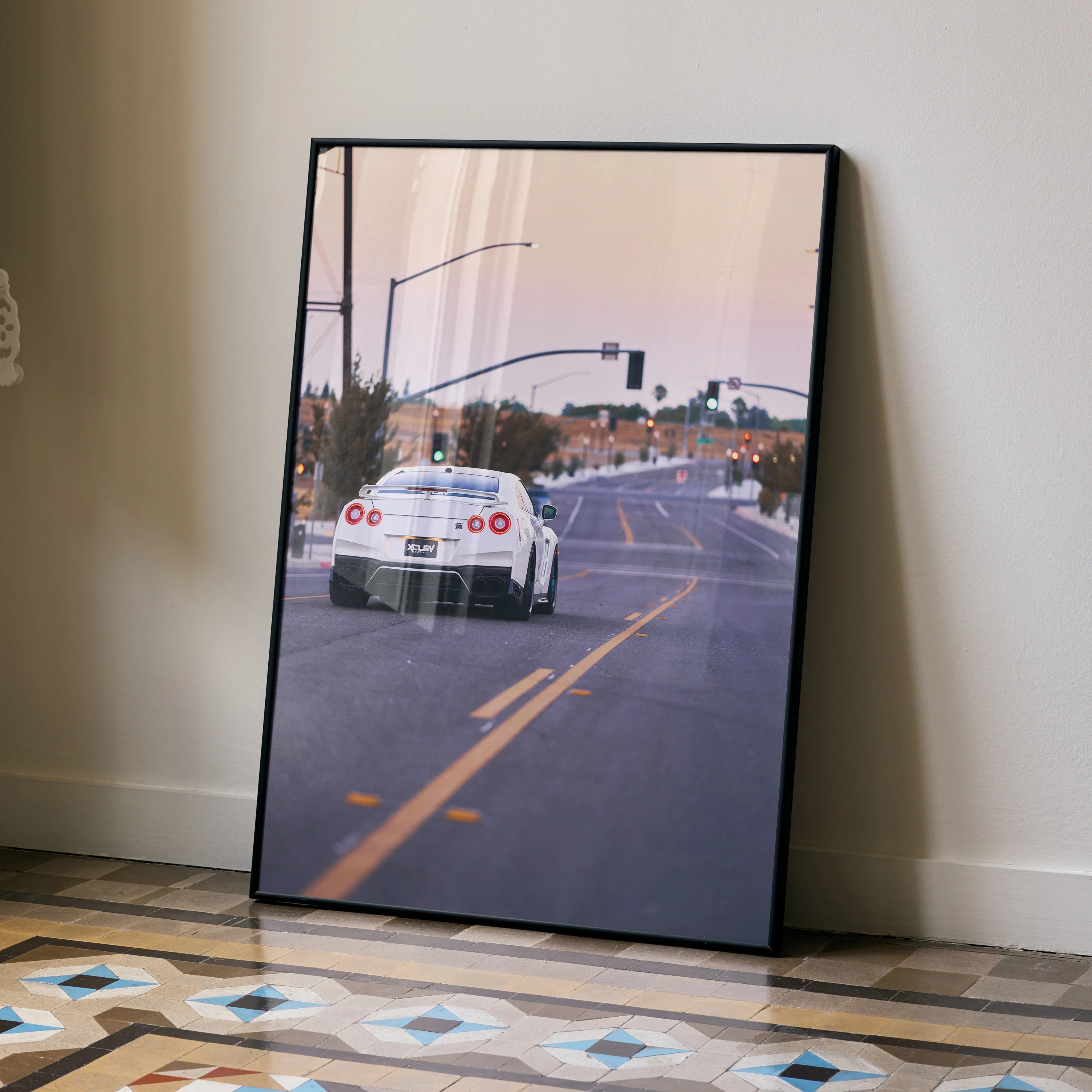 Nissan GTR R35 poster wall art featuring rear view of white sports car on city street at sunset.