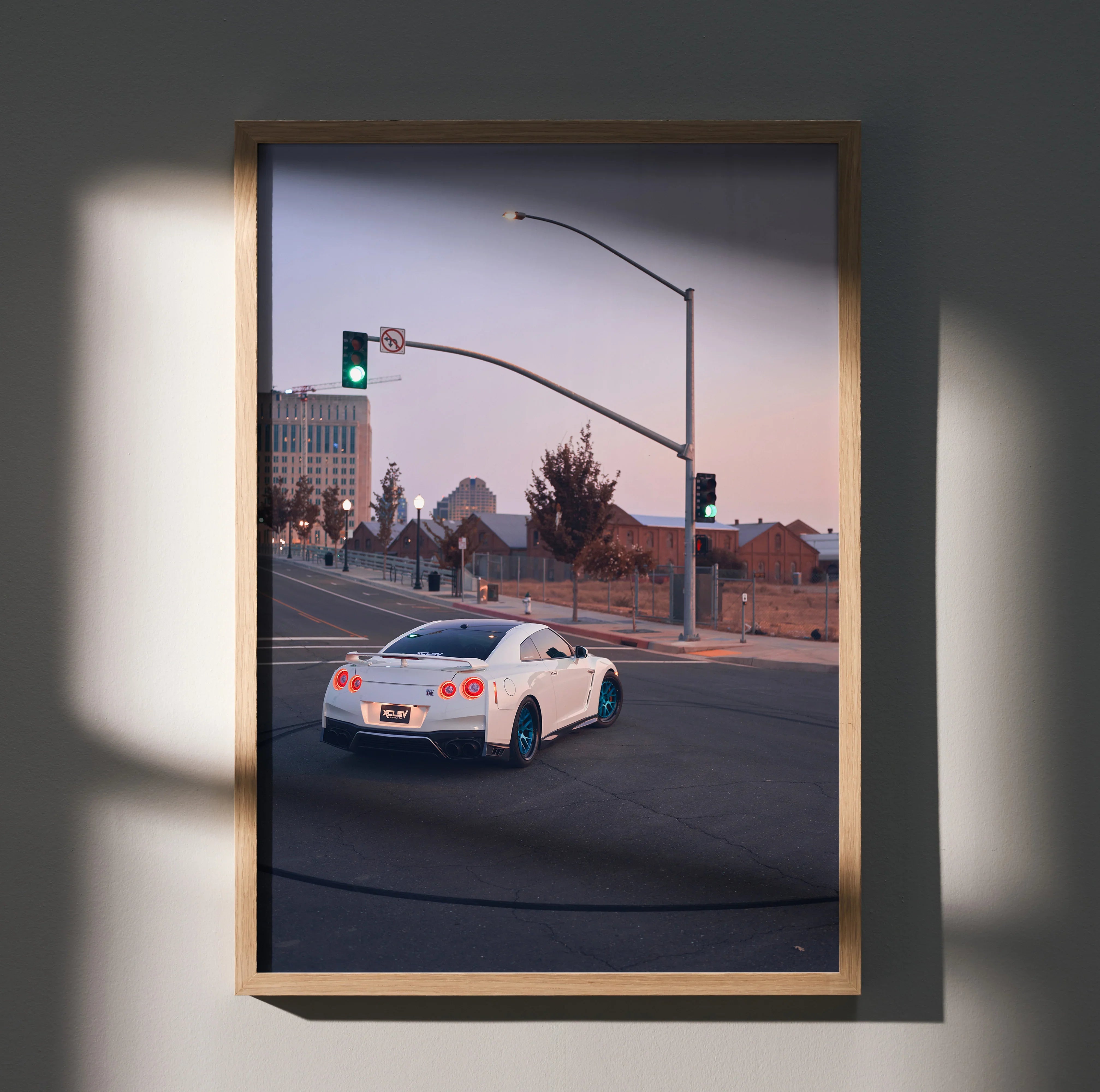 Nissan GTR R35 driving on city street at dusk poster wall art in wooden frame.