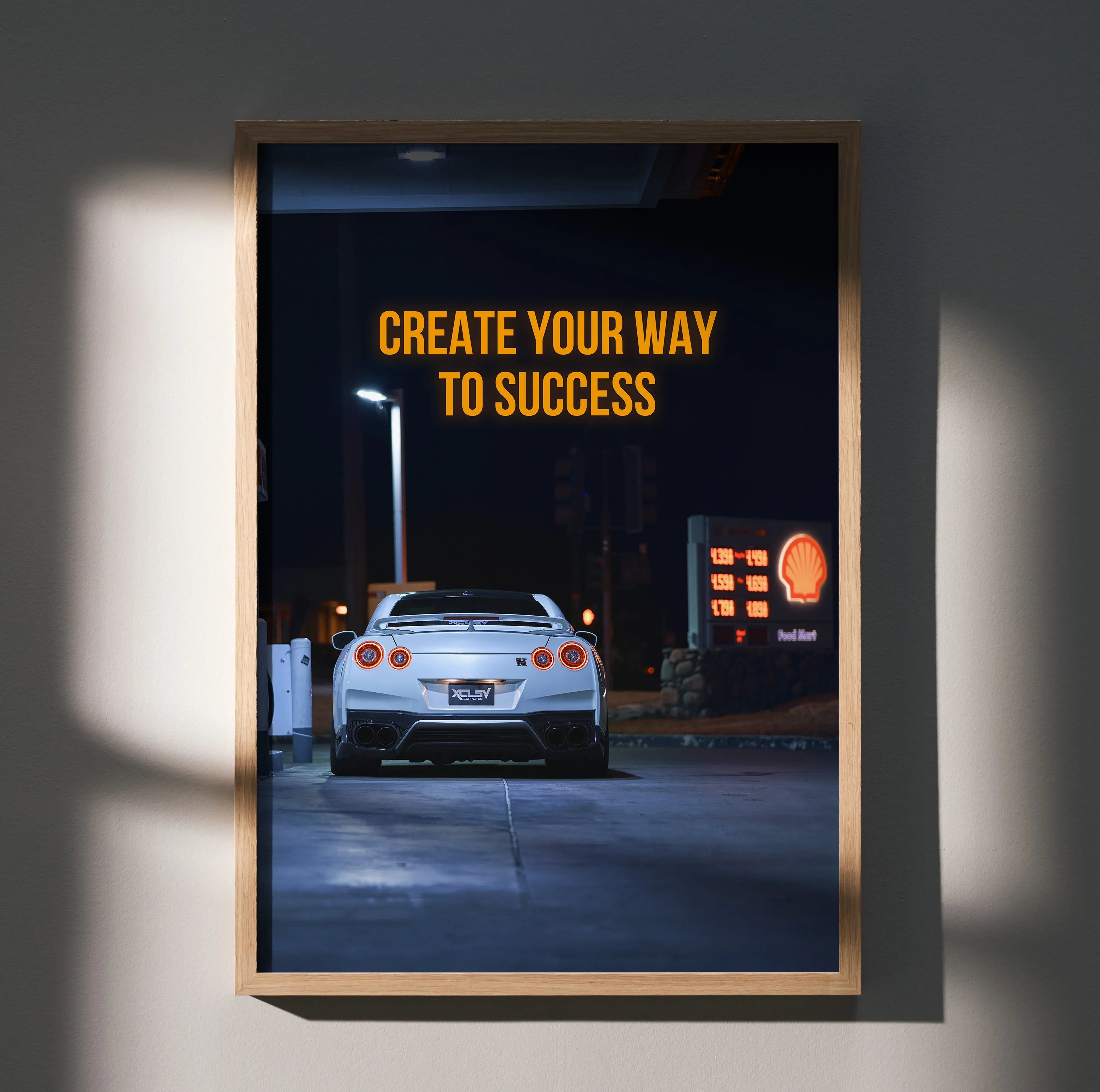 Motivational poster wall art featuring rear view of white Nissan R35 GT-R at gas station with inspiring text.