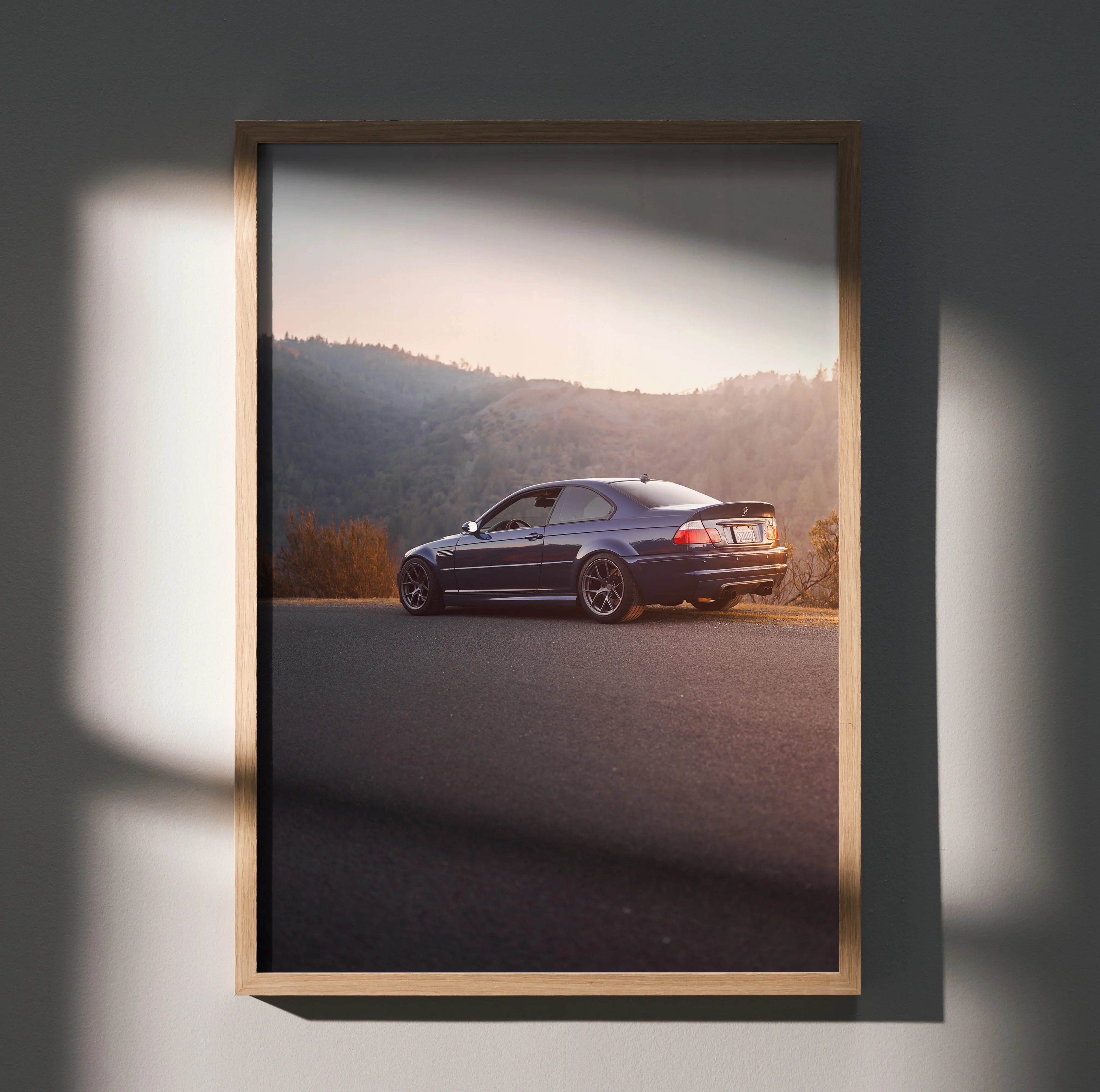 BMW E46 M3 parked on road at sunset, framed poster wall art with mountainous background.