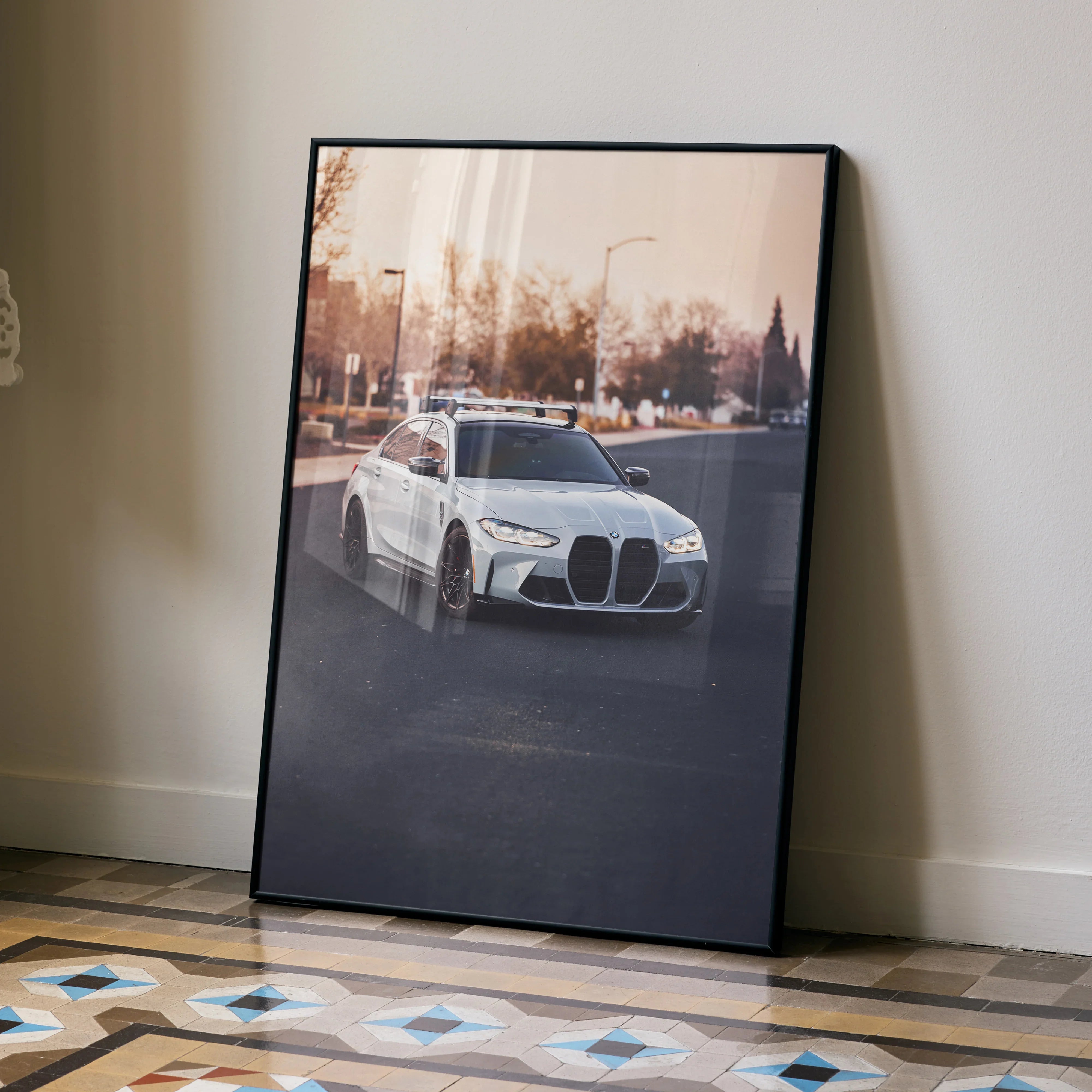BMW G80 M3 poster with luxury wall art showing silver car against sunset urban background.
