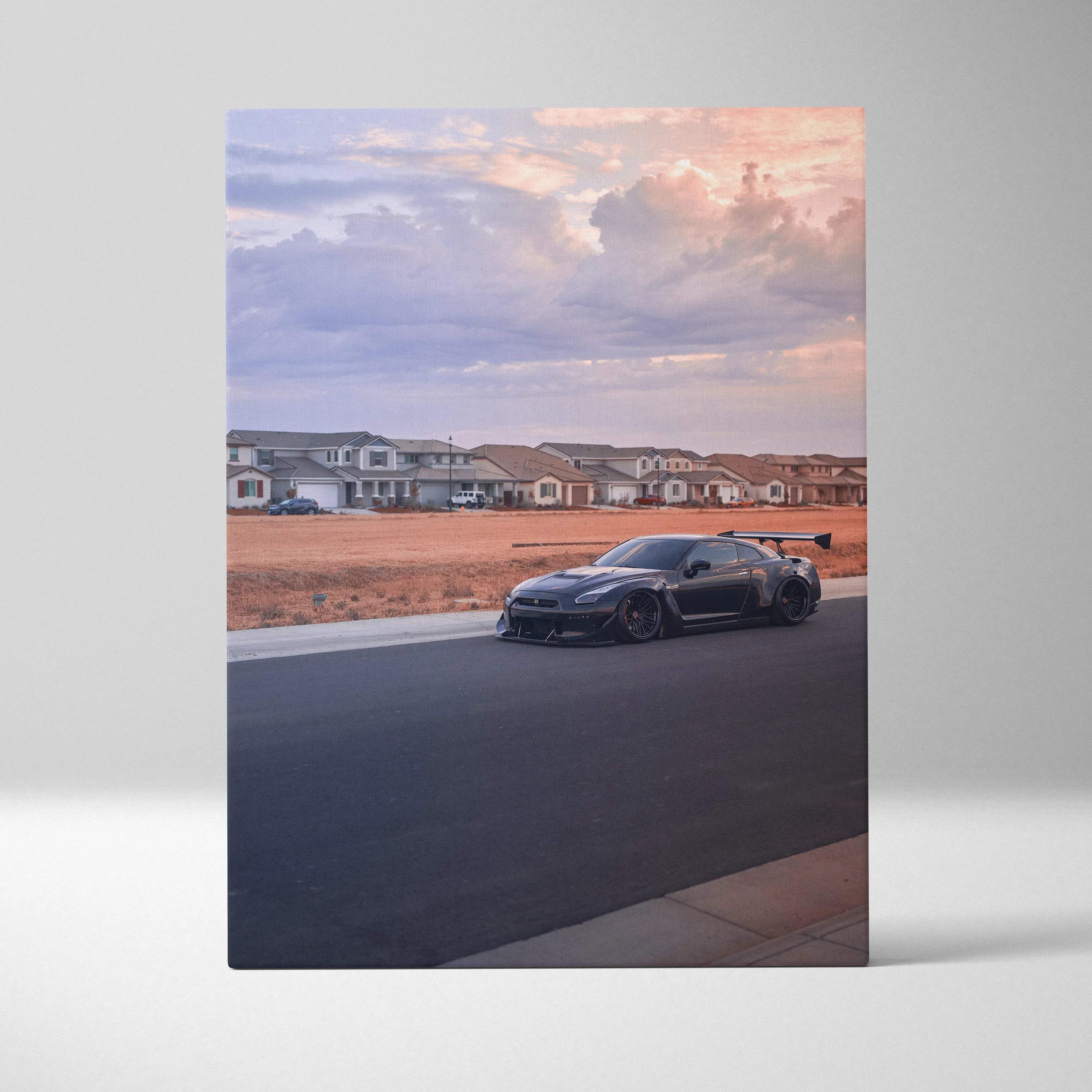 Canvas wall art featuring a dark gray nissan gt-r with a prominent rear wing on a suburban street under a cloudy sky