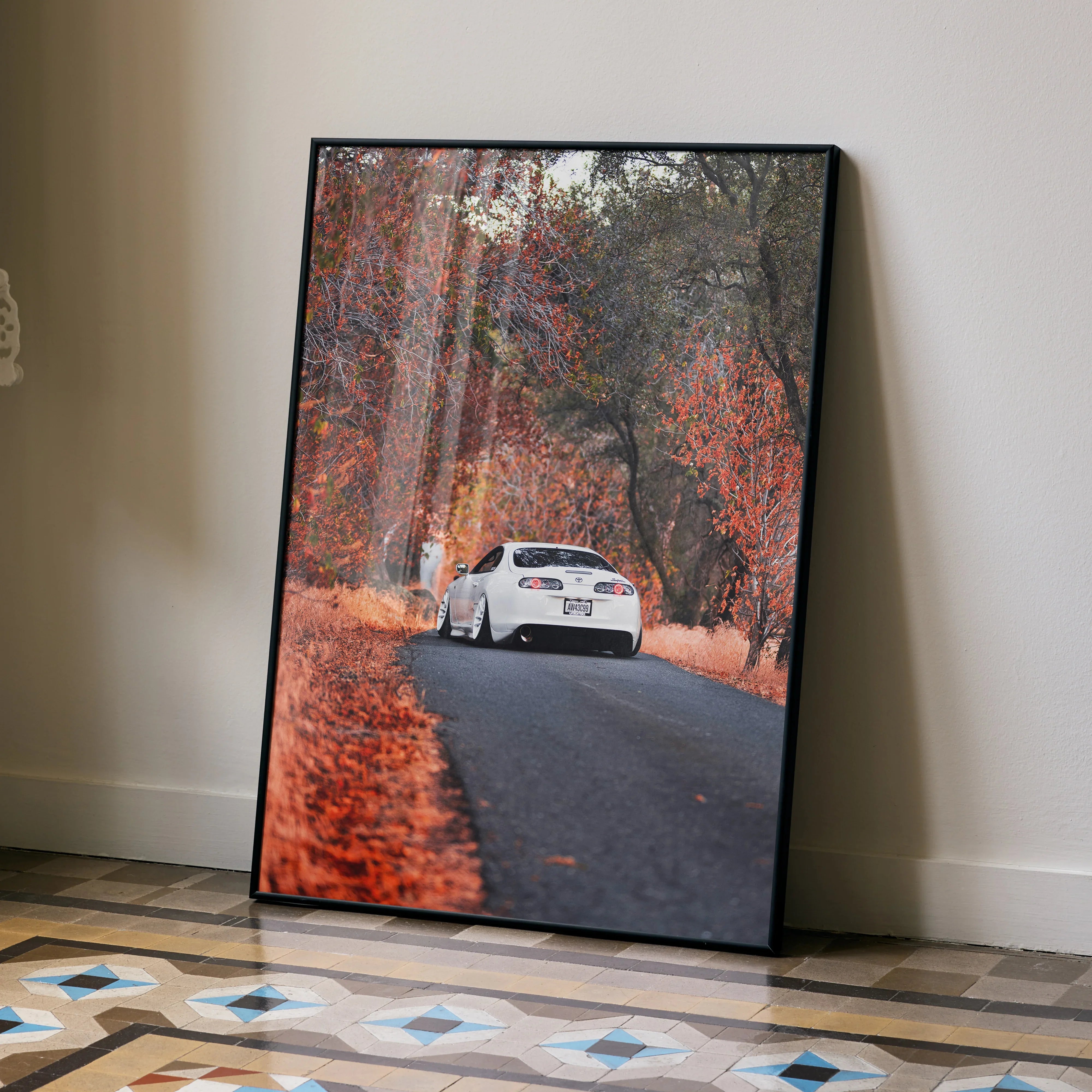 Toyota Supra MK4 driving on autumn road poster with vibrant fall foliage wall art.