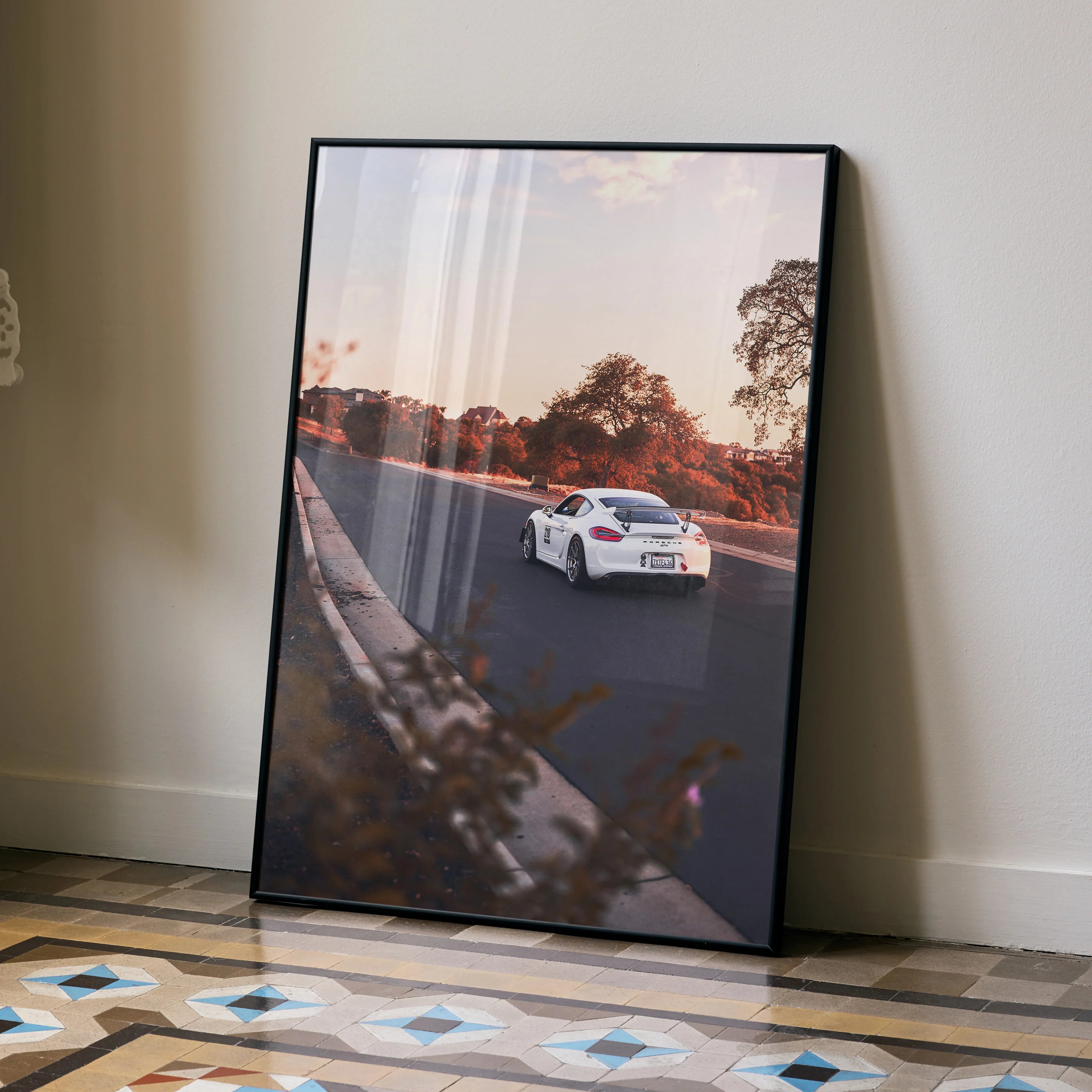 Porsche GT4 driving on road at sunset poster wall art with autumn trees and black frame.