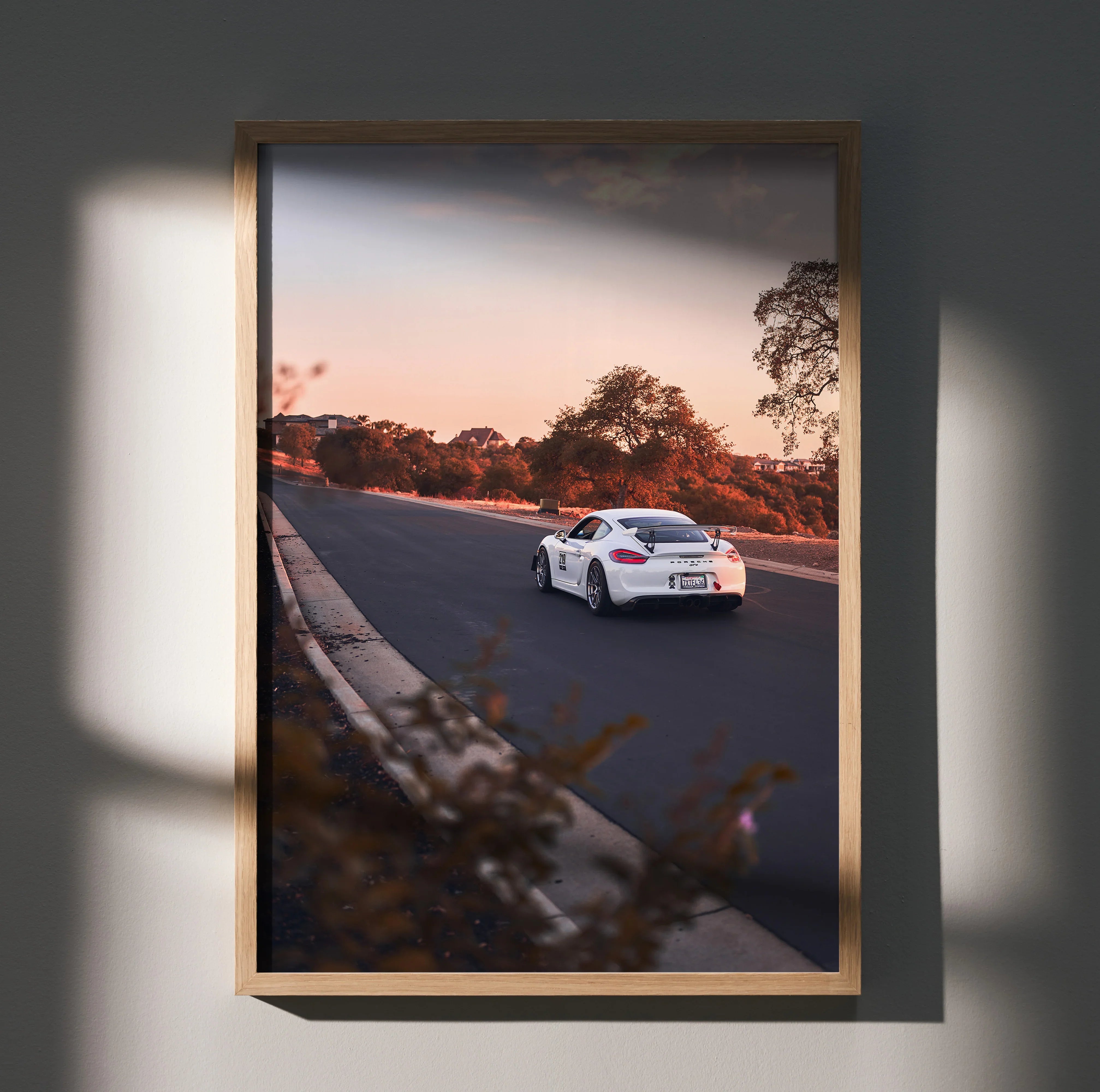 Porsche GT4 driving on road at sunset framed as premium wall art poster with warm tones.