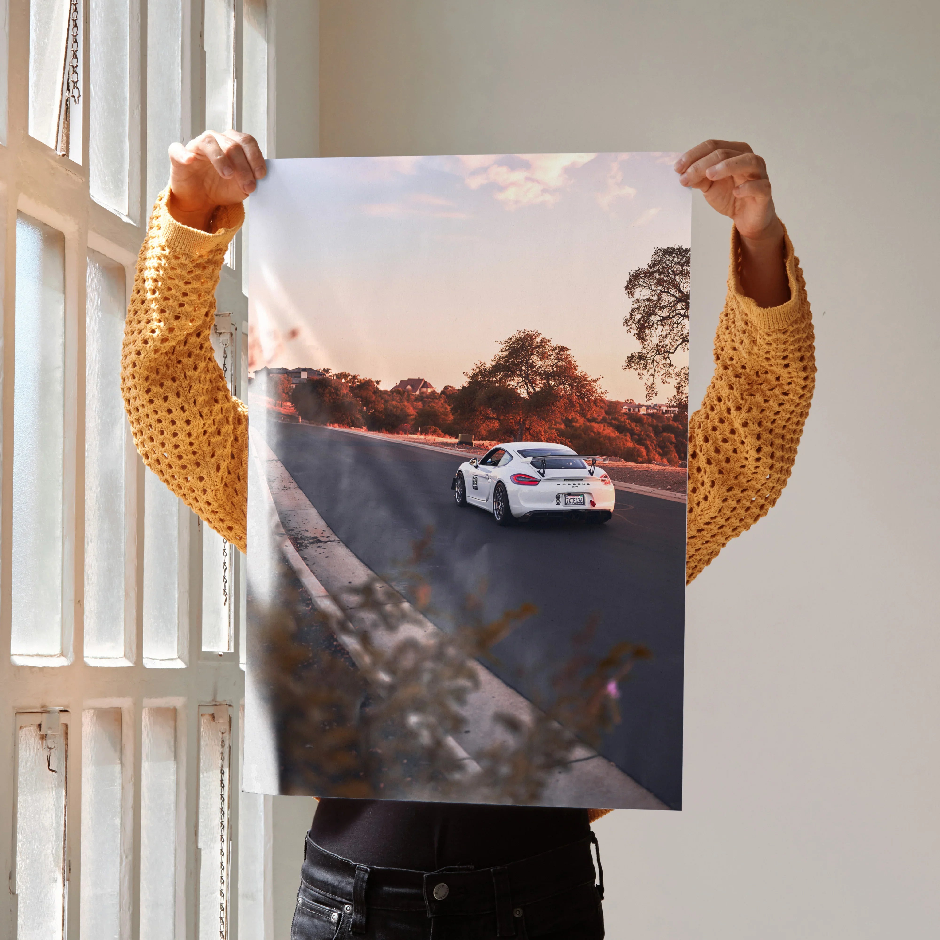 Porsche GT4 driving on a sunset road poster wall art with vibrant sky and trees.
