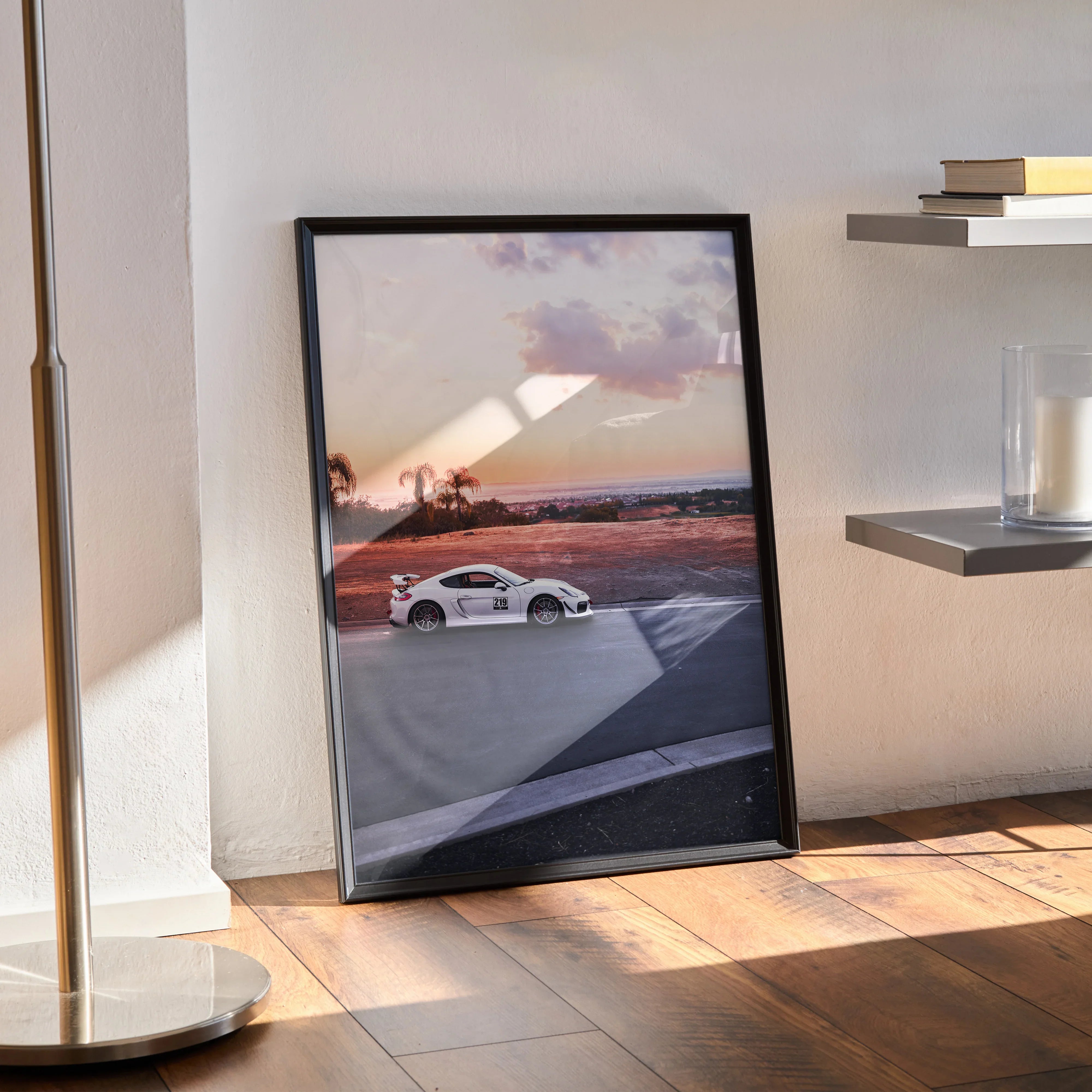 Porsche GT4 racing car poster with sunset background in black frame wall art leaning against wall.