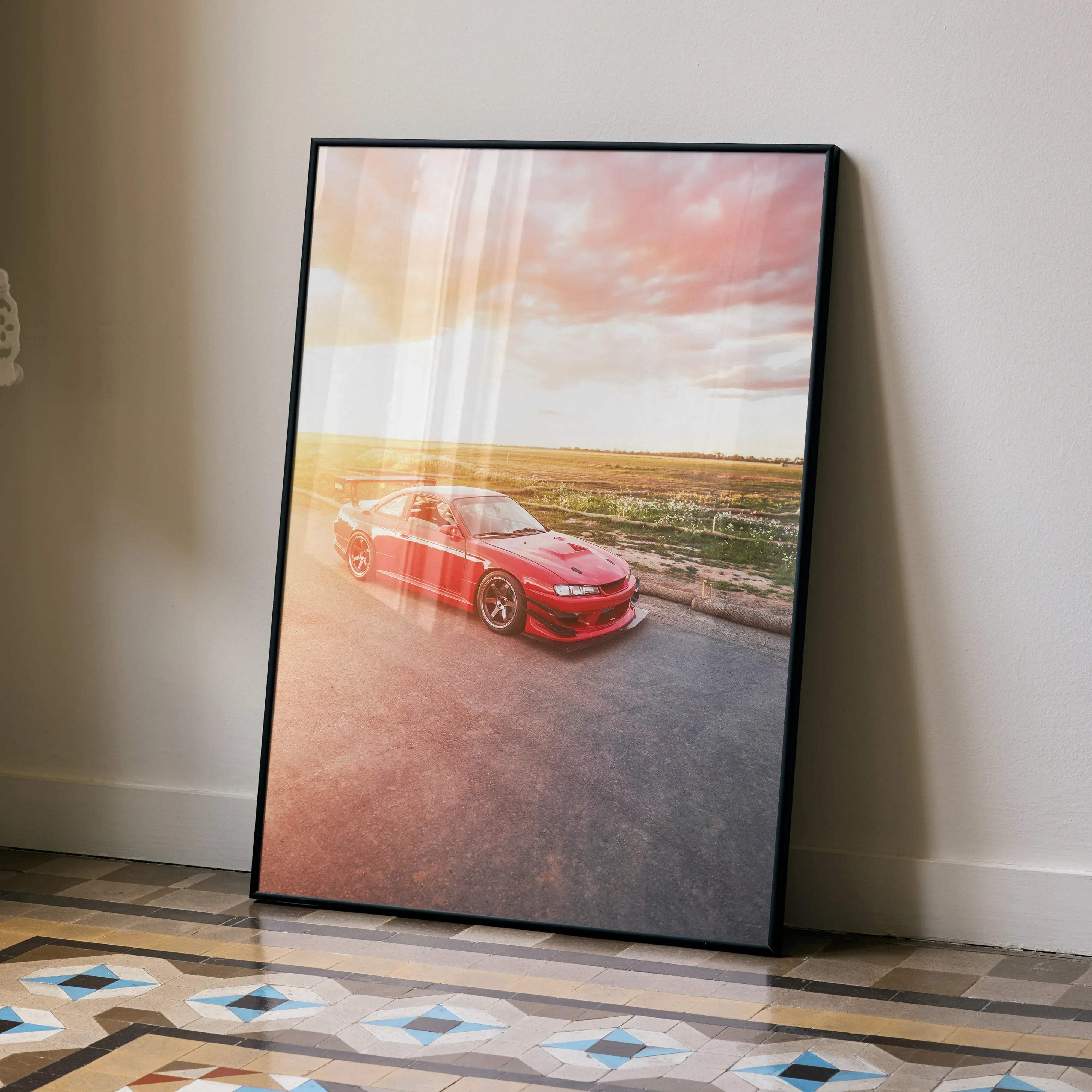 A framed high resolution poster of a red Nissan 240sx S14 Kouki sports car speeding under a sunset sky