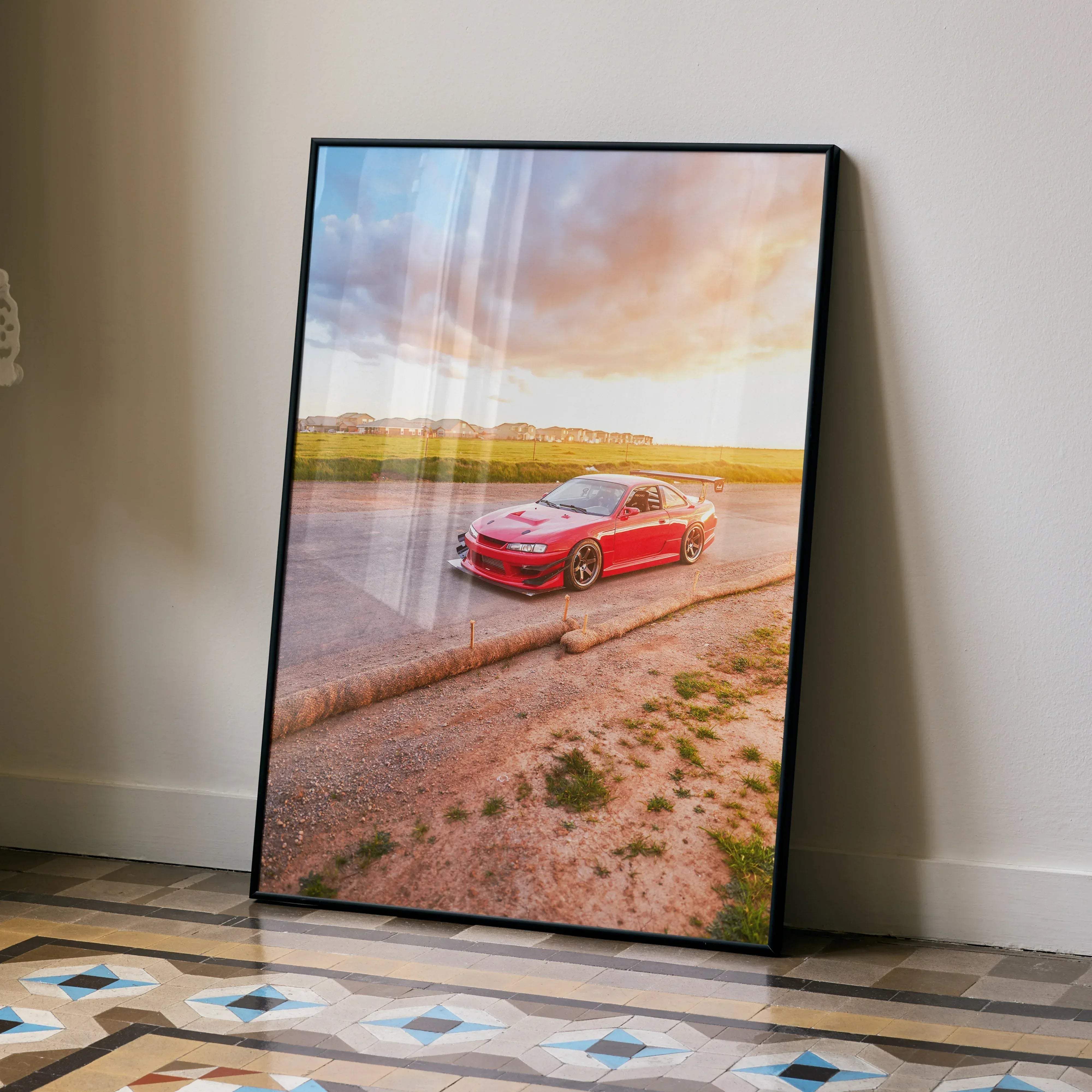 A framed high resolution poster of a red nissan 240sx s14 kouki sports car on a dirt road under a dramatic sky