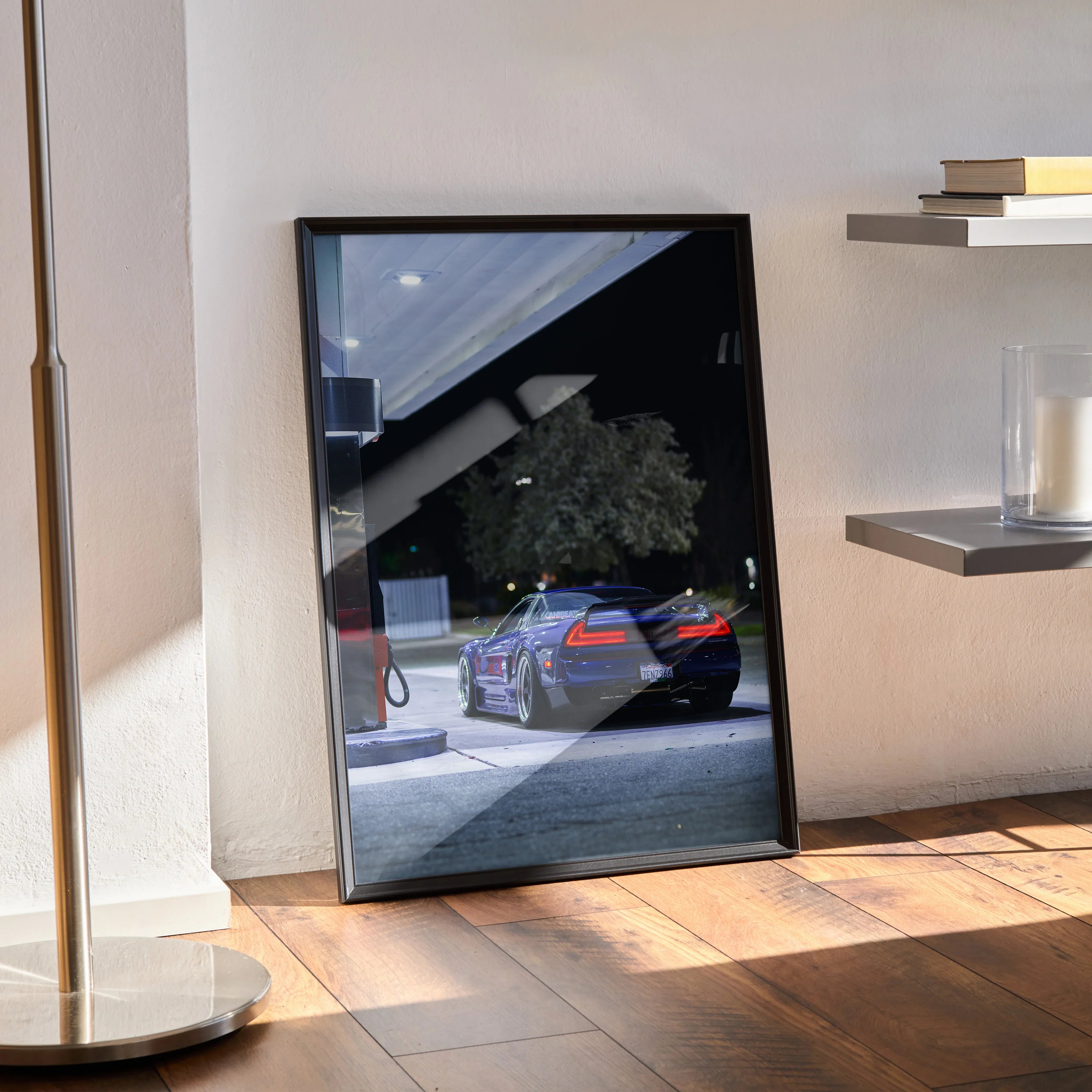 Acura NSX poster wall art with nighttime urban car scene framed in black on hardwood floor.