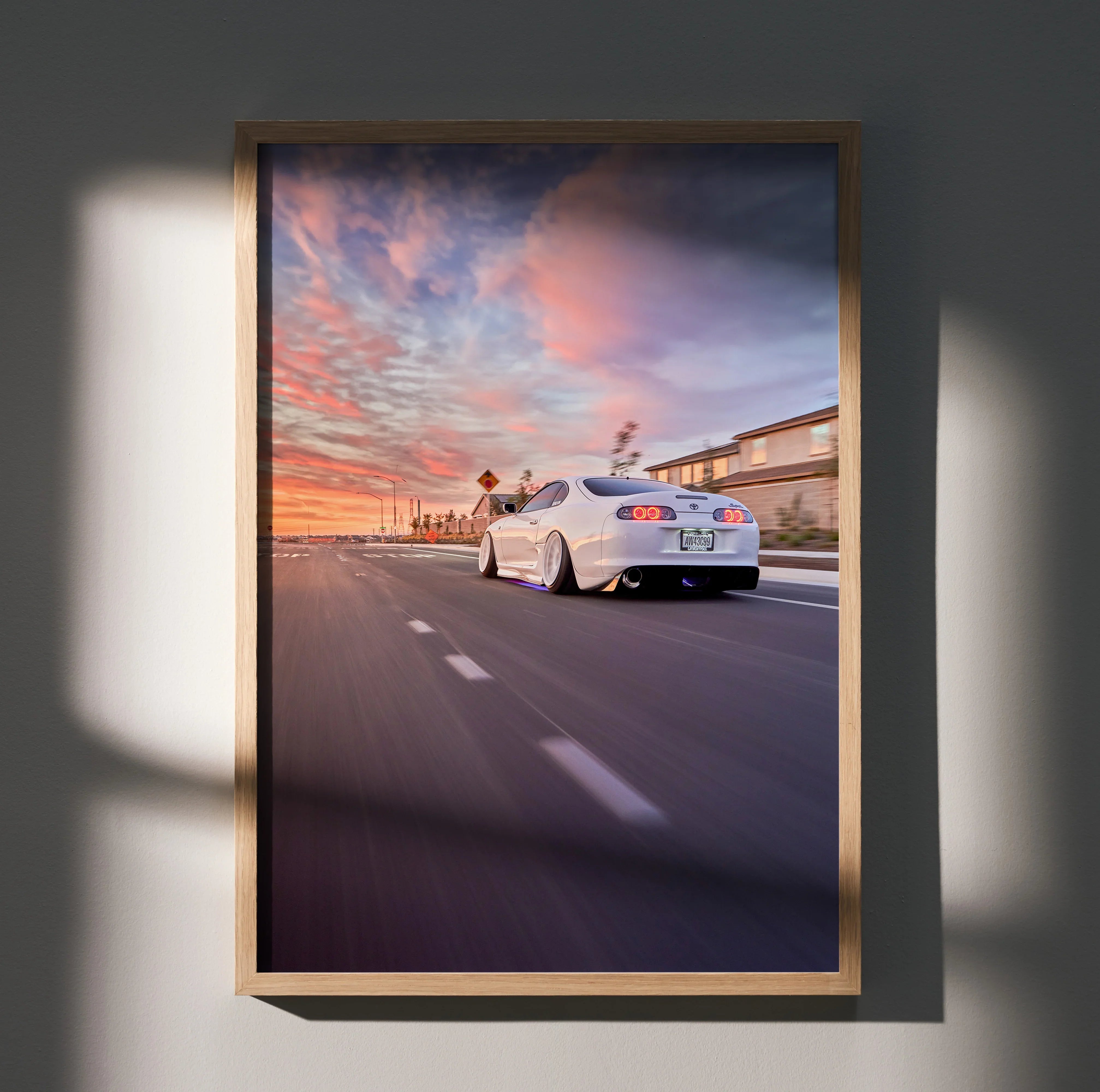 Toyota Supra MK4 driving on highway at sunset poster wall art in wooden frame.