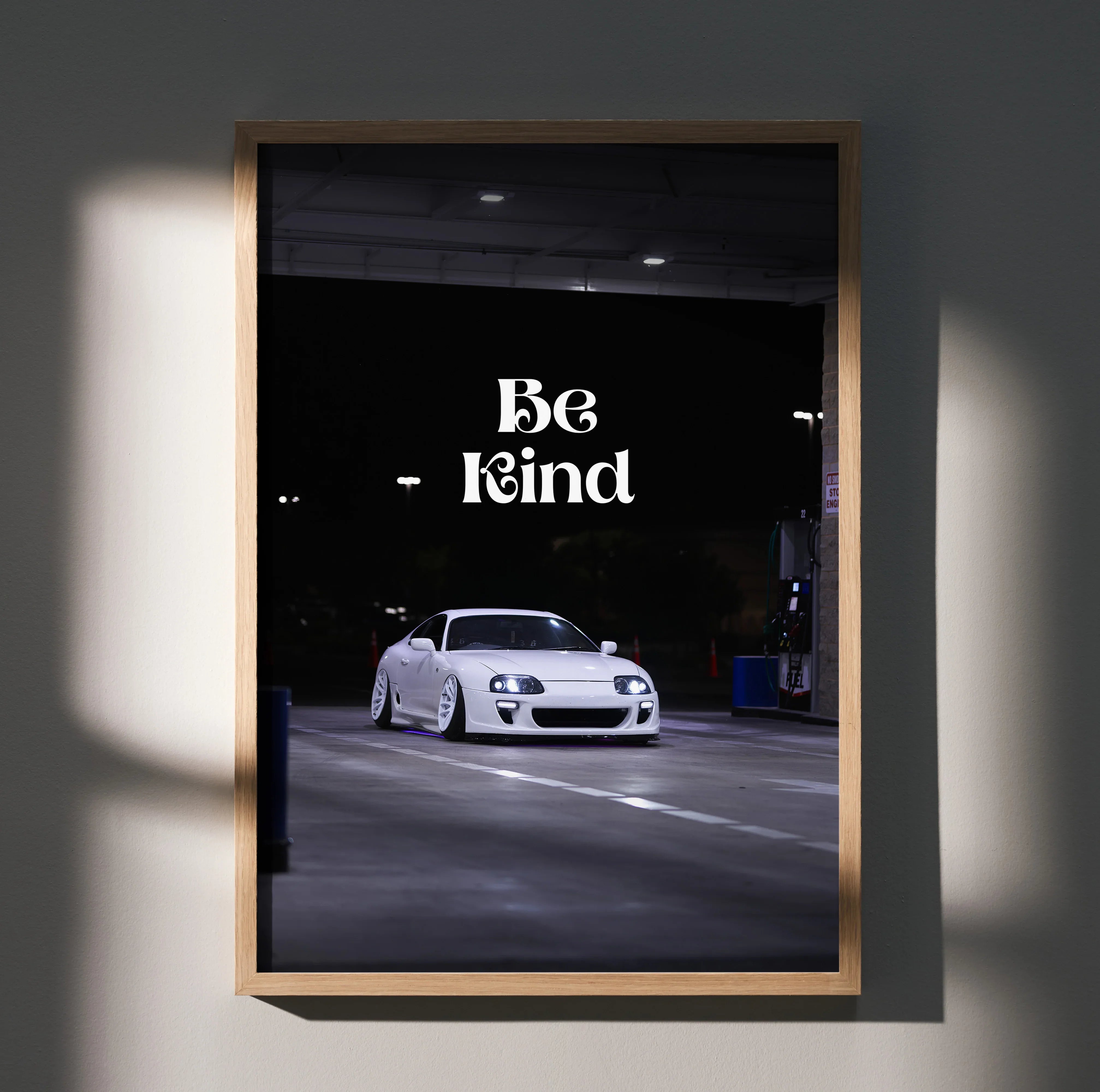 Motivational wall art poster featuring white Toyota Supra Mk4 with "Be Kind" text on black background.